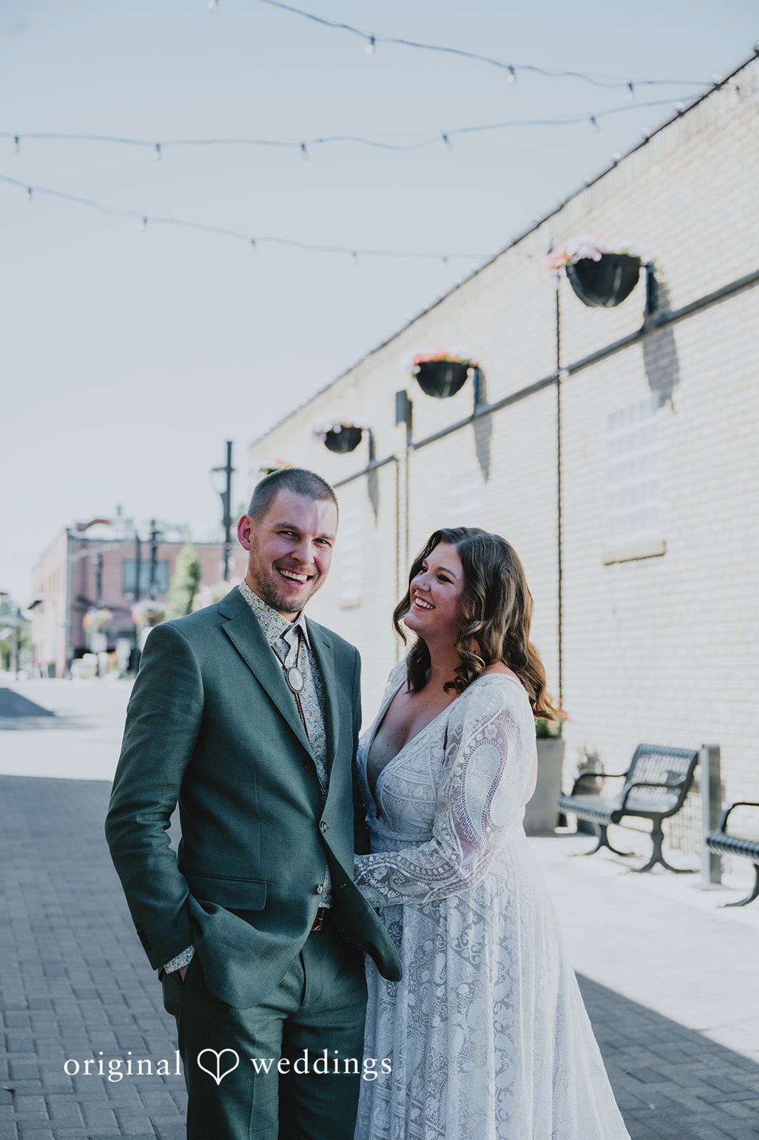 Elizabeth + Willis Bride and groom smiling and posing in front of a bright white wall.