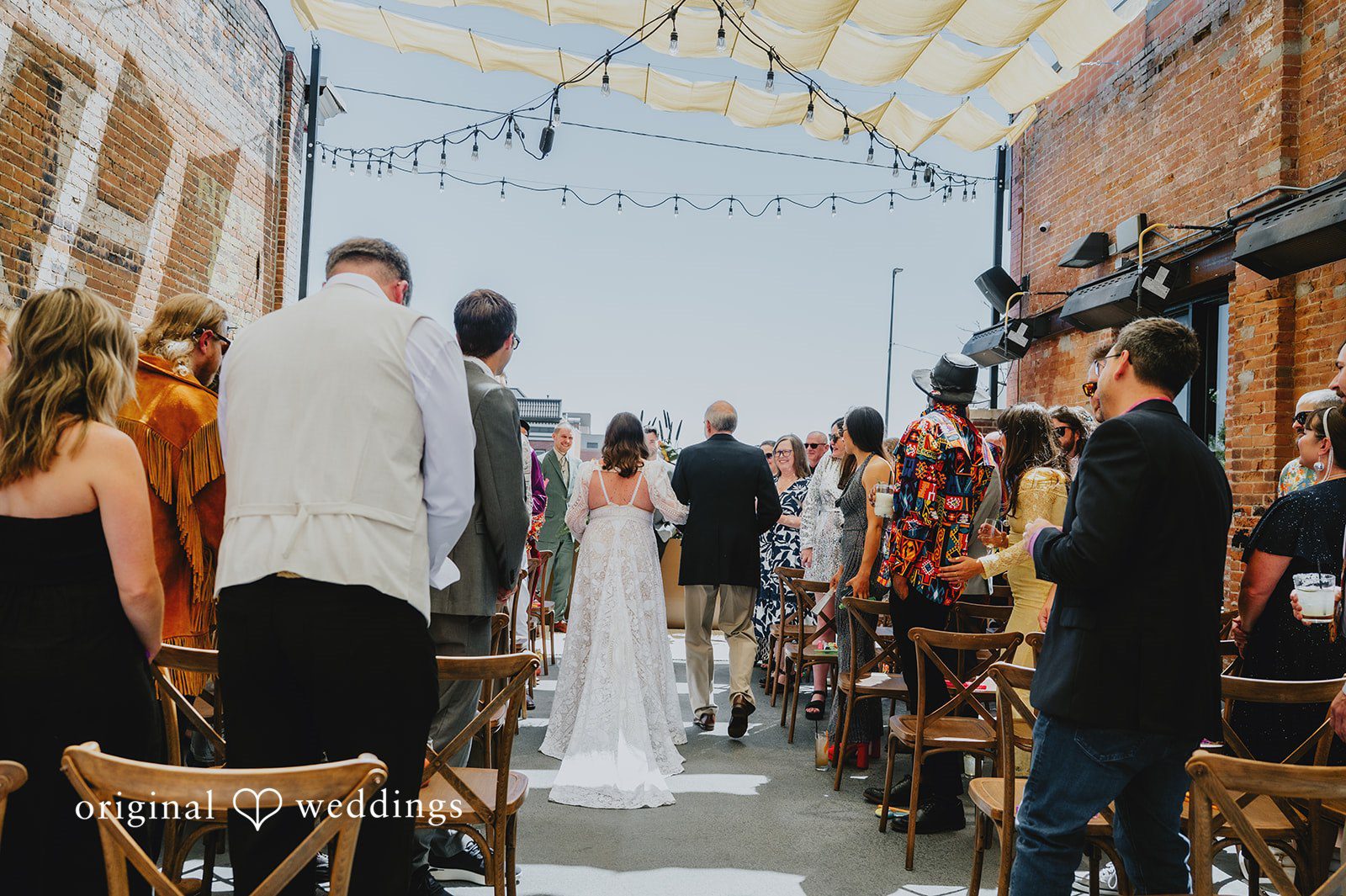Elizabeth + Willis Guests standing along a decorated aisle looking toward the back of the venue.