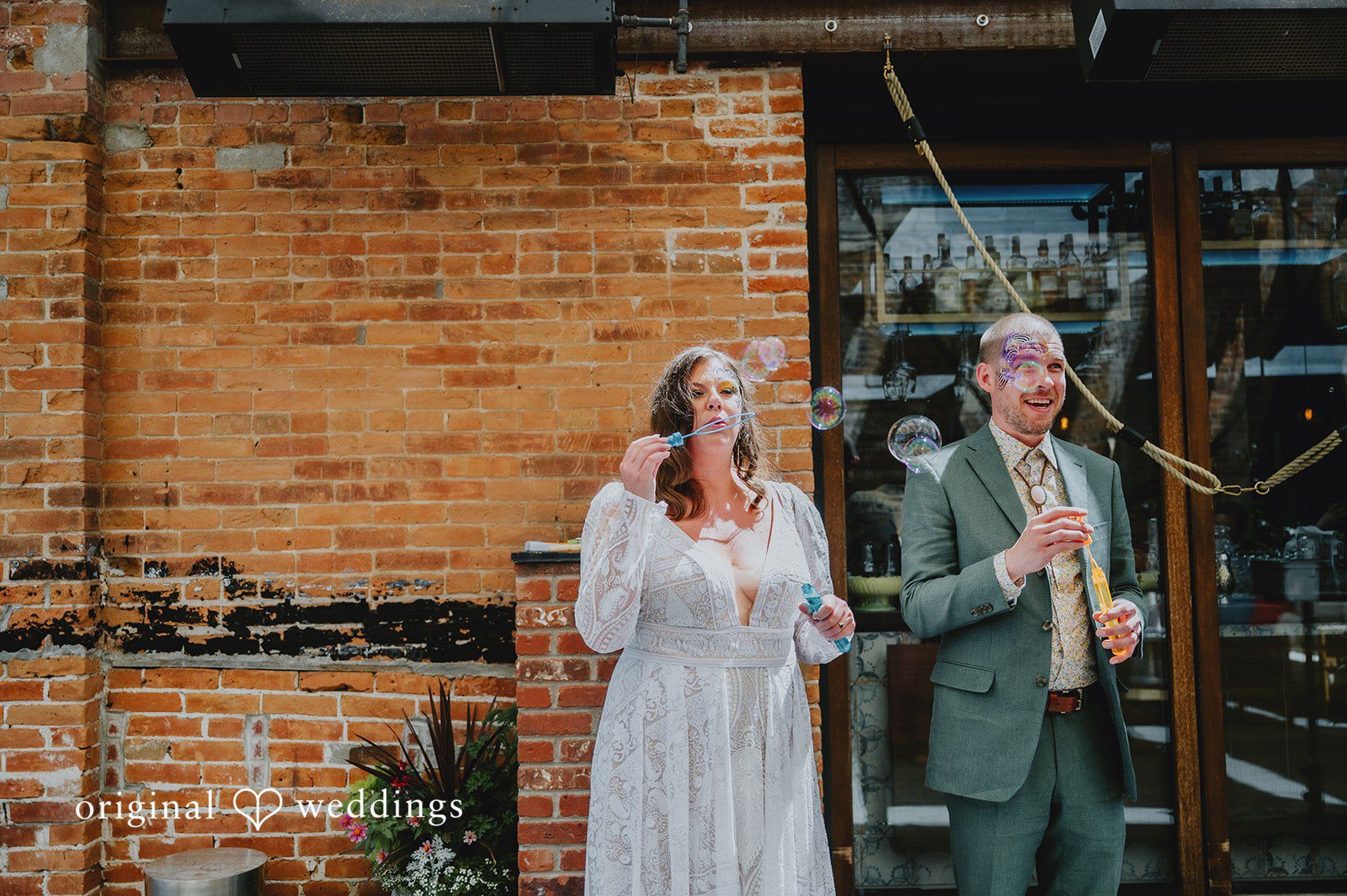 Elizabeth + Willis Couple standing close together next to a textured brick wall.
