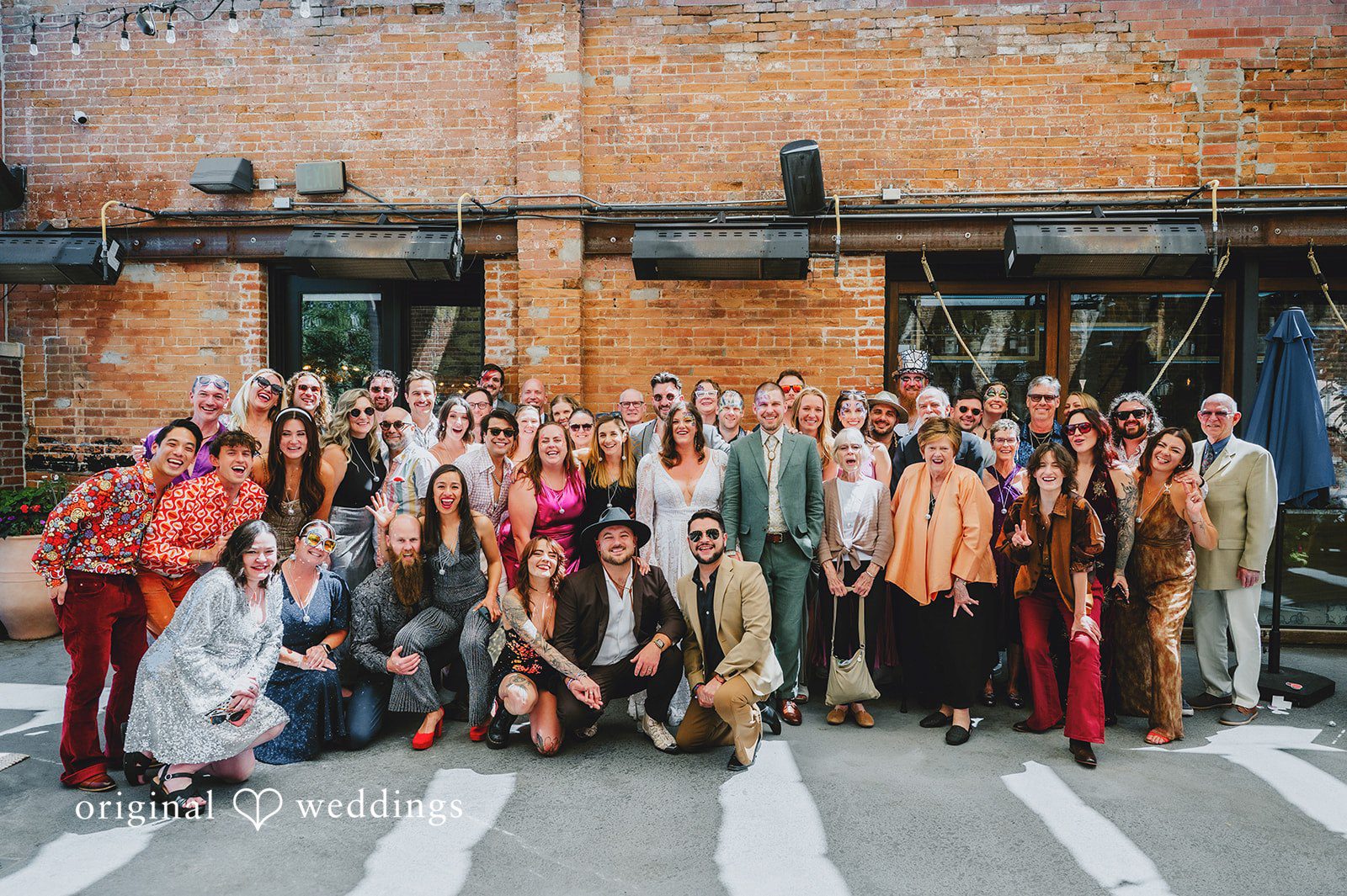 Elizabeth + Willis Large group of wedding guests posing together for a group photo on a street.