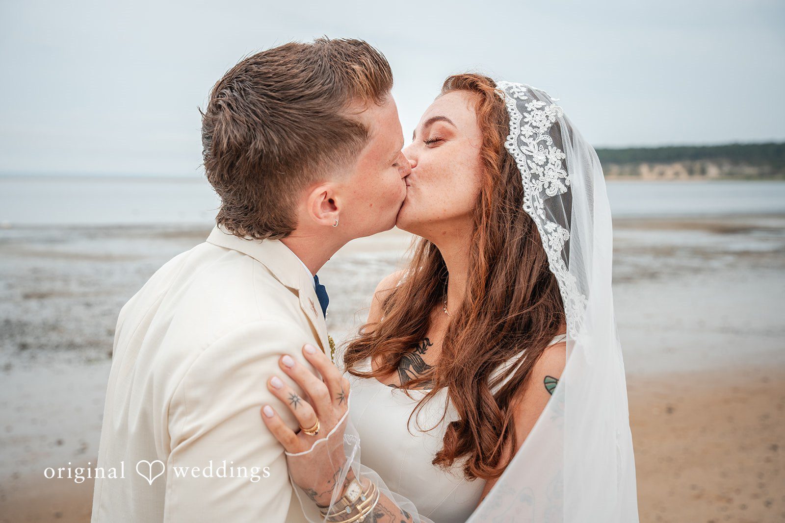 Jacqueline + Sarah A close-up shot of a wedding couple kissing affectionately on the beach.