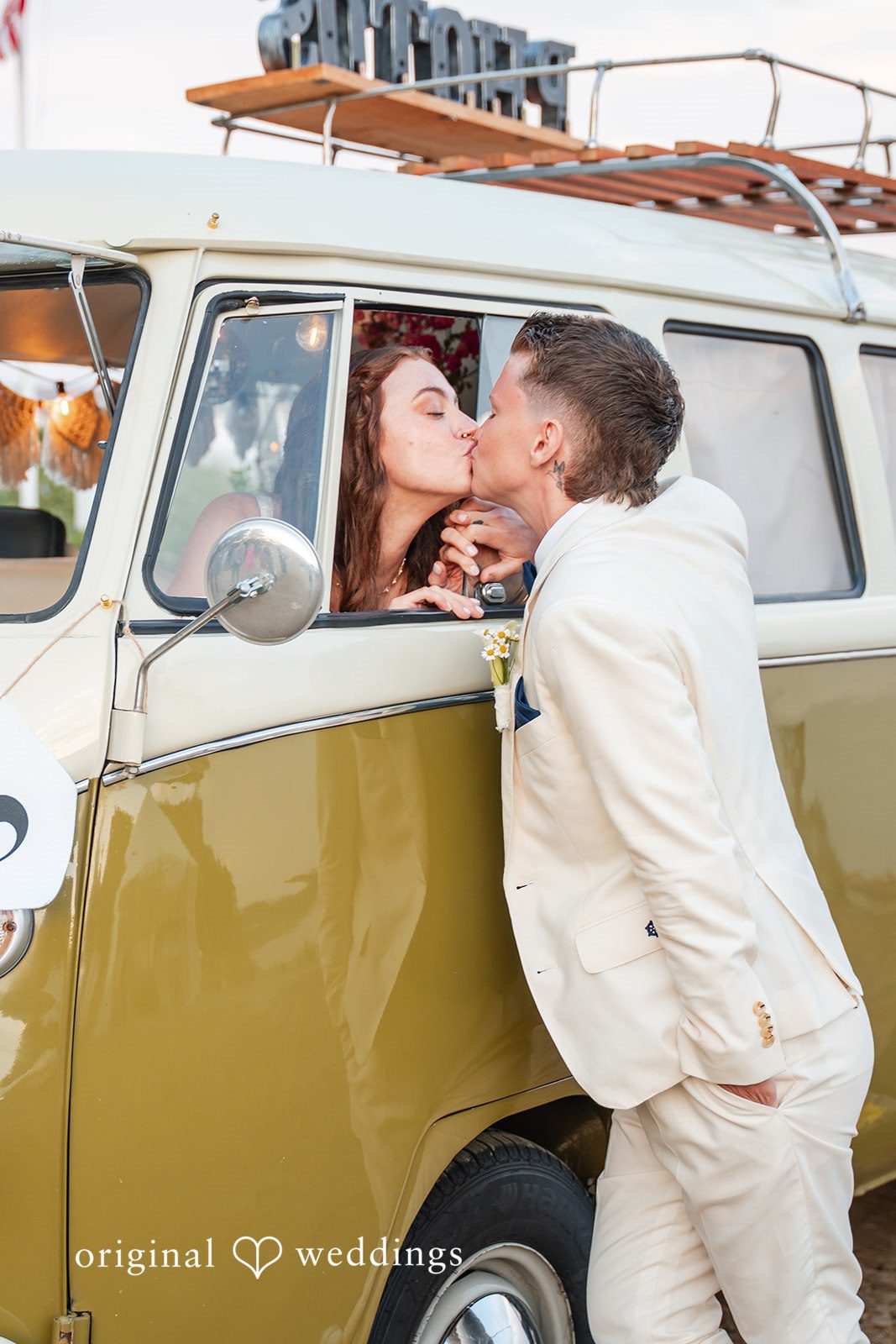 Jacqueline + Sarah A wedding couple leaning out of a vintage van window to share a kiss.