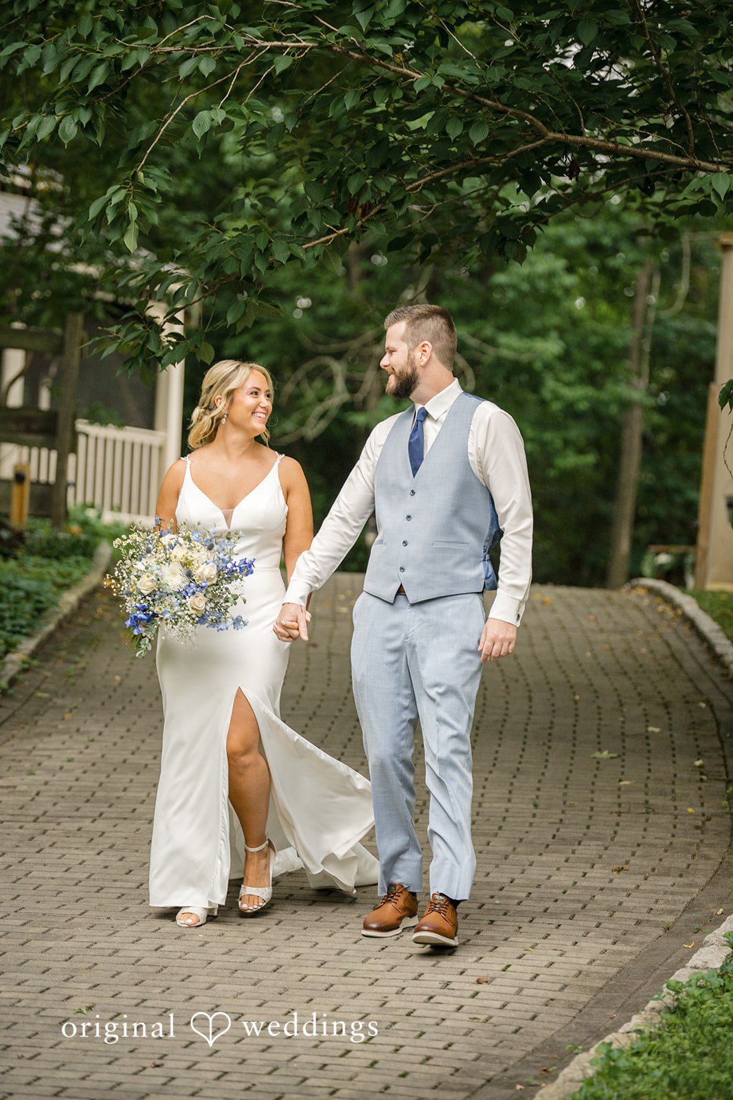 Morgan + Colin A bride and groom holding hands and walking together along a paved path.