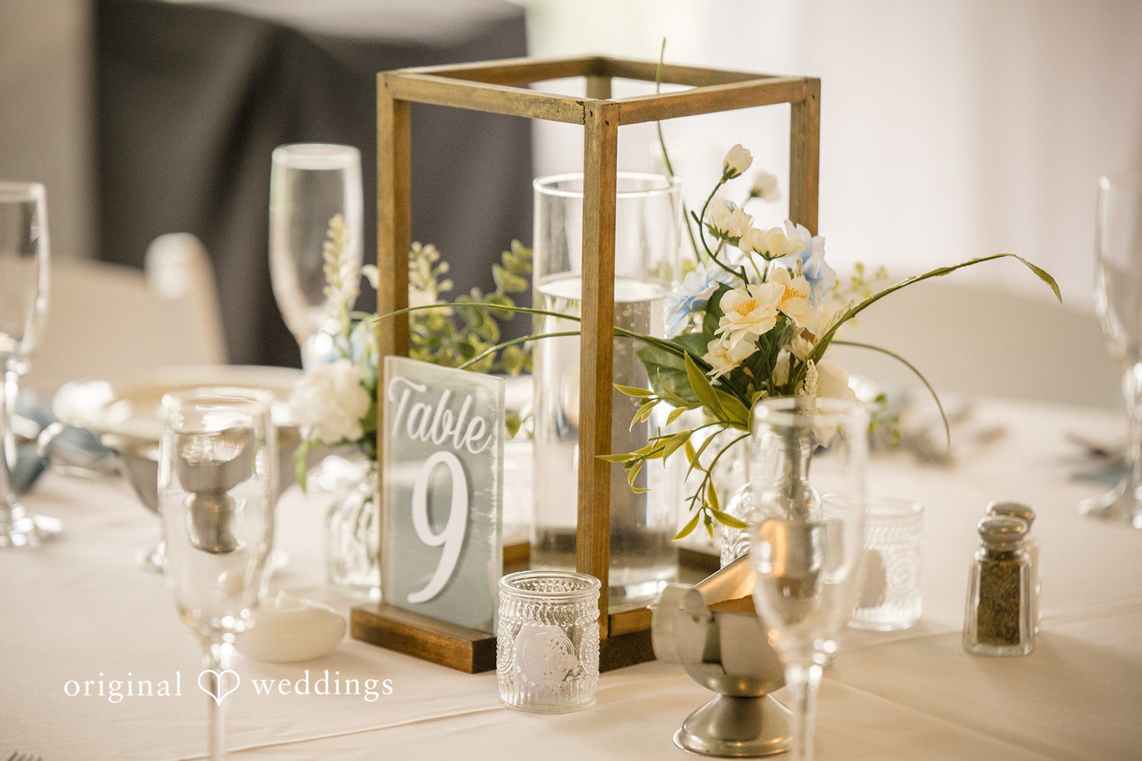 Morgan + Colin A close-up of wedding centerpieces featuring glass vases and tall candles.