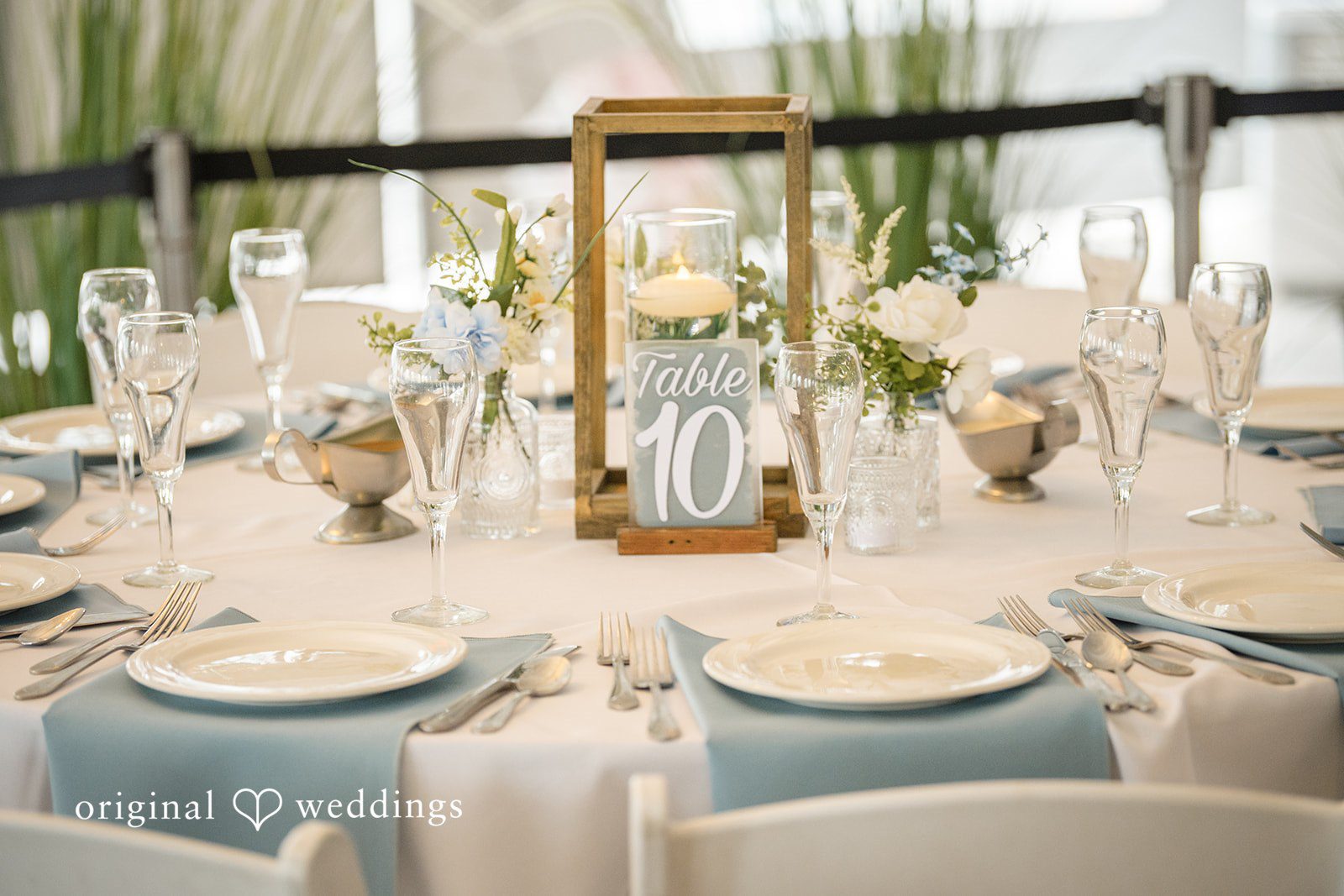 Morgan + Colin A circular reception dining table elegantly set with blue and gold accents.