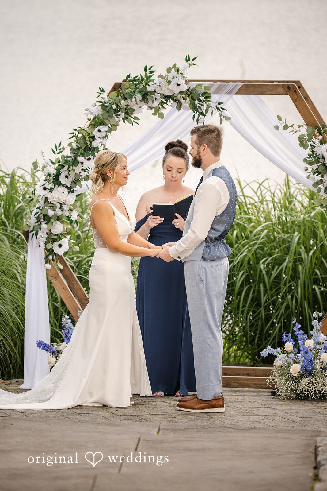 Morgan + Colin A bride and groom holding hands while reciting their vows during the ceremony.