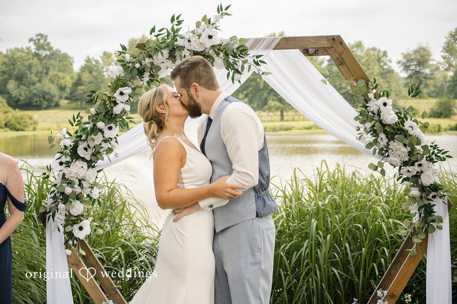 Morgan + Colin A newly married bride and groom embracing happily under a decorated arch.