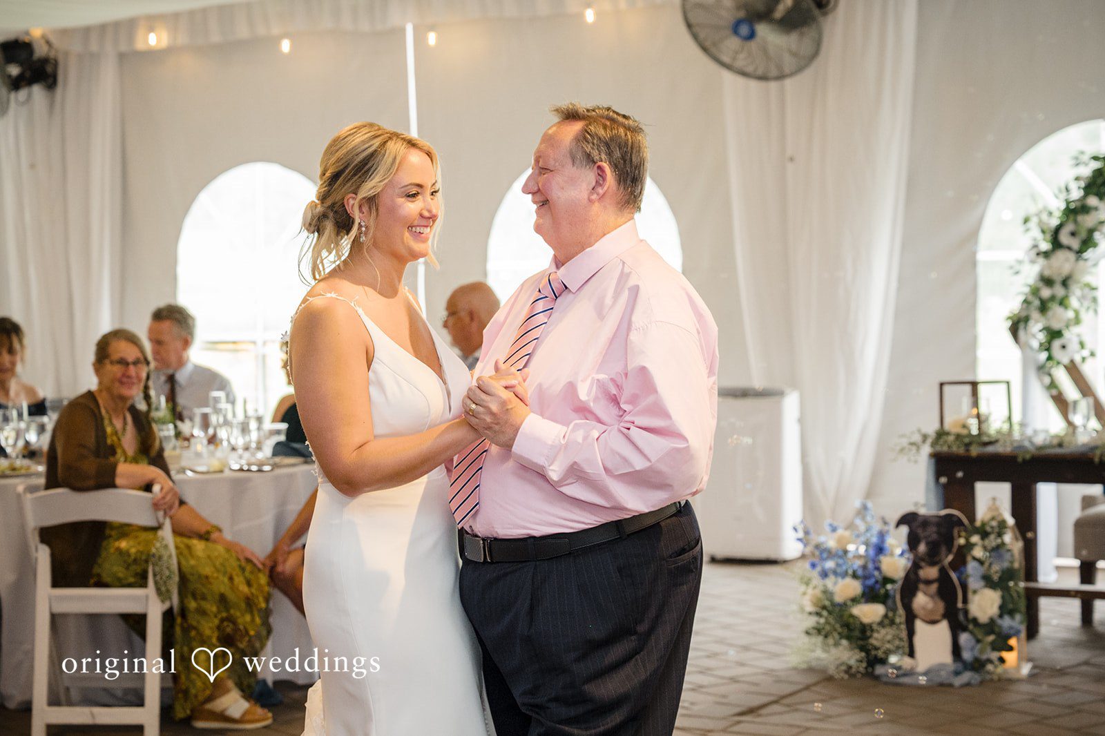 Morgan + Colin A bride smiling while dancing with a male guest in a pink shirt at the reception.
