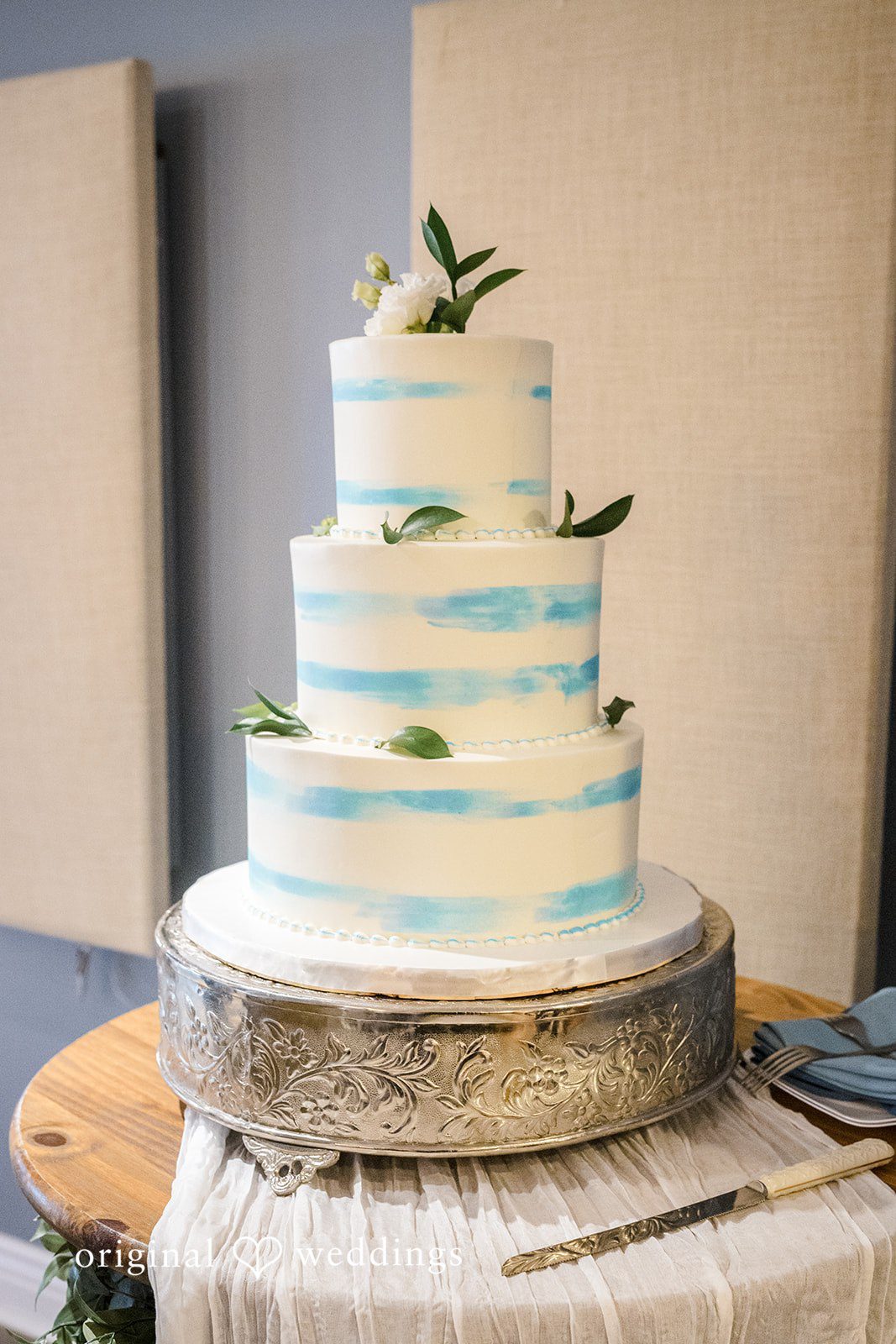 Morgan + Colin A multi-tiered white wedding cake decorated with subtle blue watercolor brushstrokes.