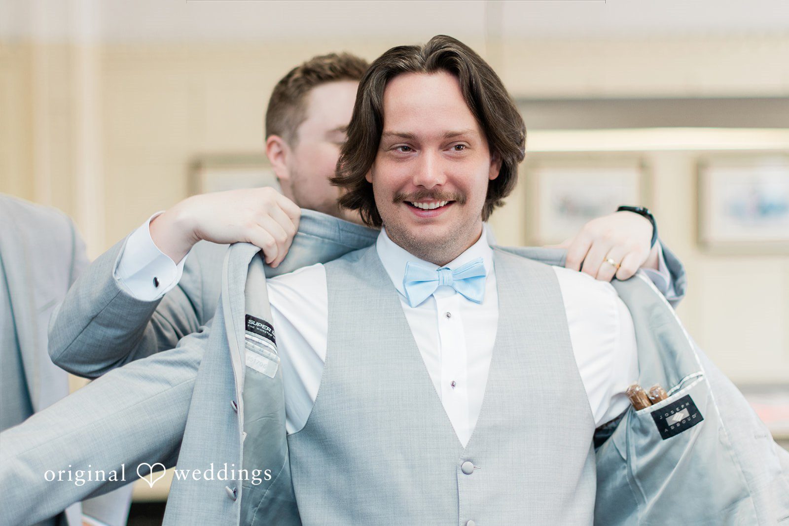 Sara + Michael Groomsmen assisting the groom as he puts on his light blue suit jacket.