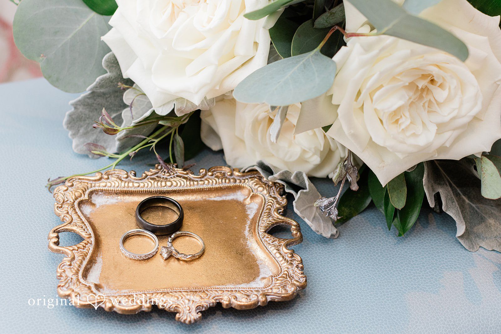 Sara + Michael Two wedding rings placed inside a small, ornate vintage tray next to white roses.