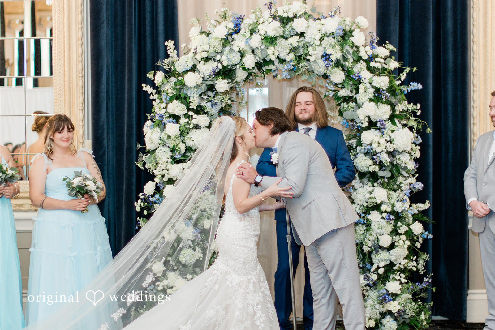 Sara + Michael A bride and groom sharing a kiss at the altar framed by a large circular floral arch.