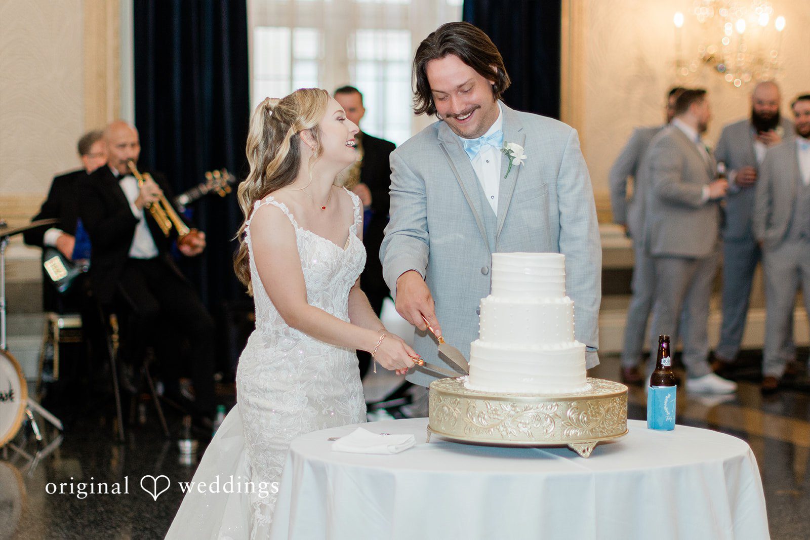 Sara + Michael A bride and groom standing together to cut their tall white wedding cake.