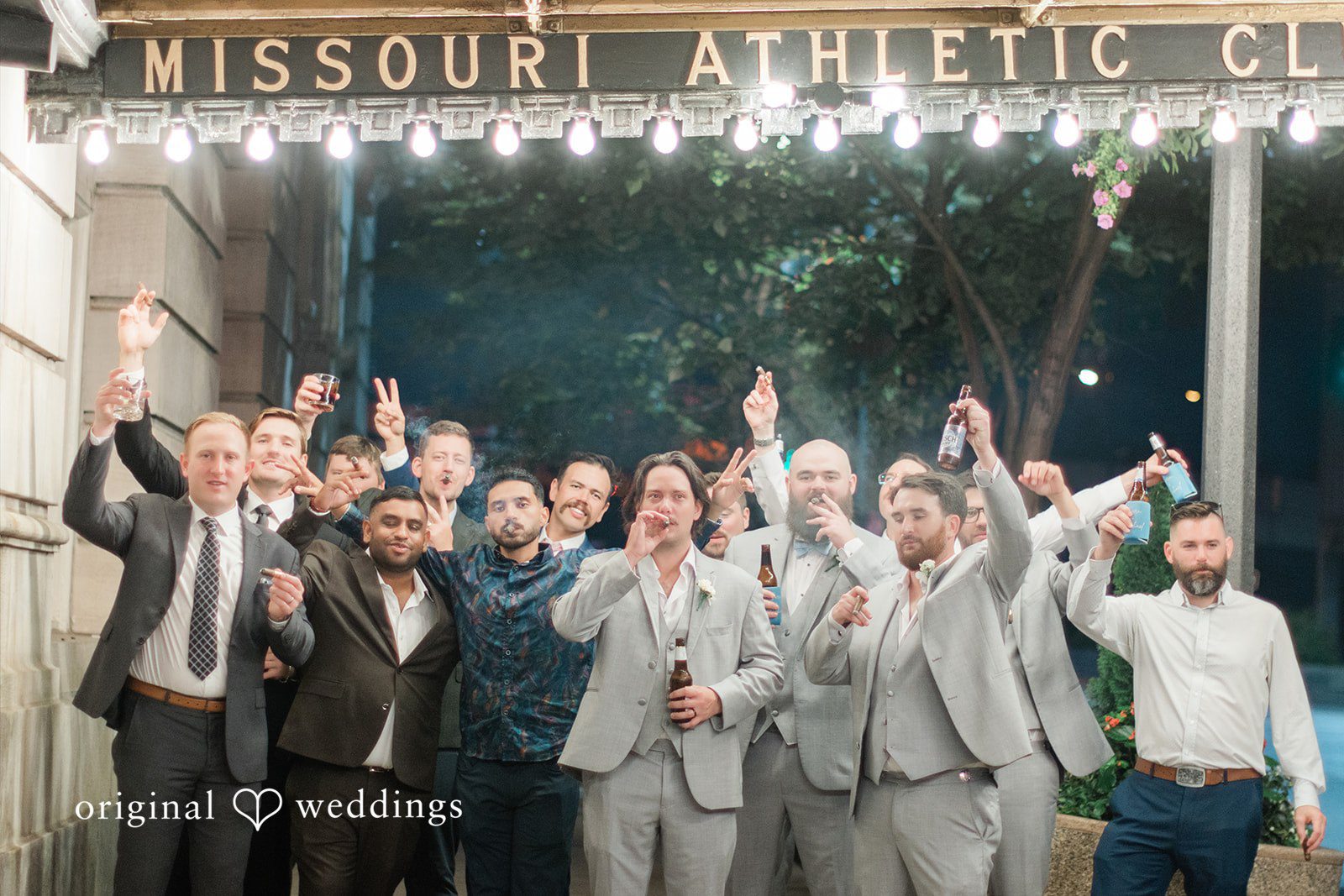 Sara + Michael A groom posing cheerfully with a large group of cheering groomsmen.