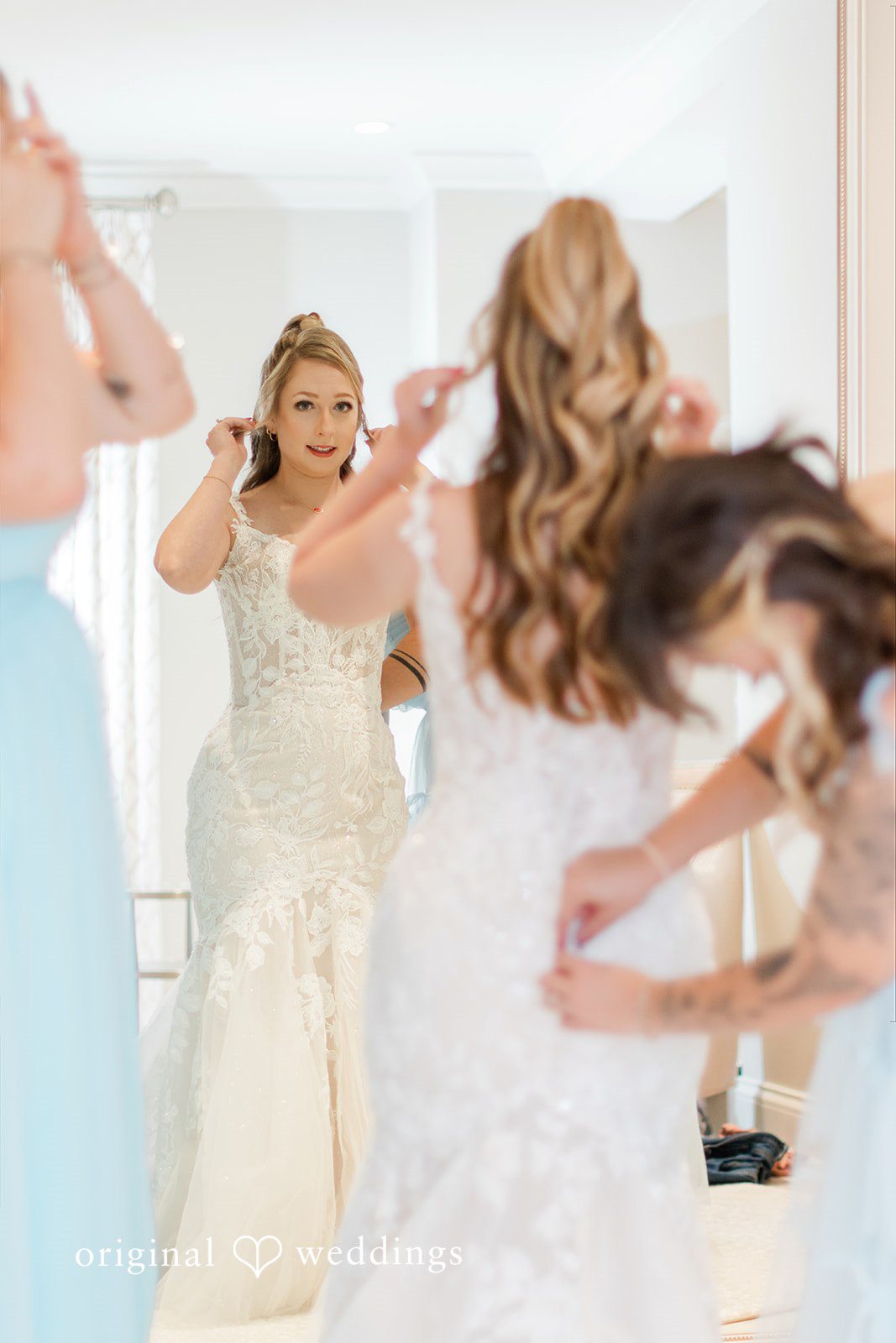 Sara + Michael A bride looking into a large mirror while adjusting her wedding dress.