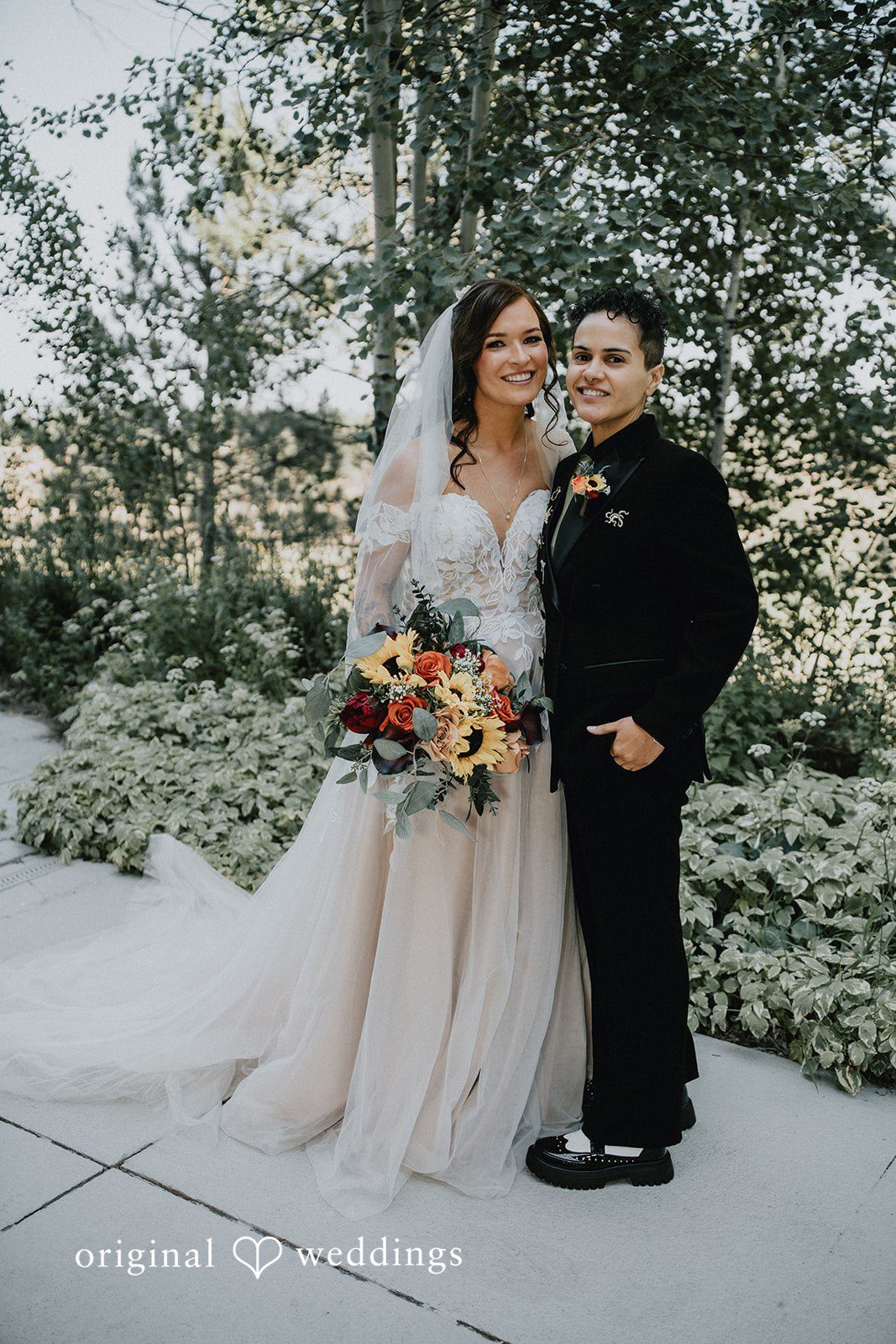Jennifer + Danielle Couple pose together while standing in a grassy area.