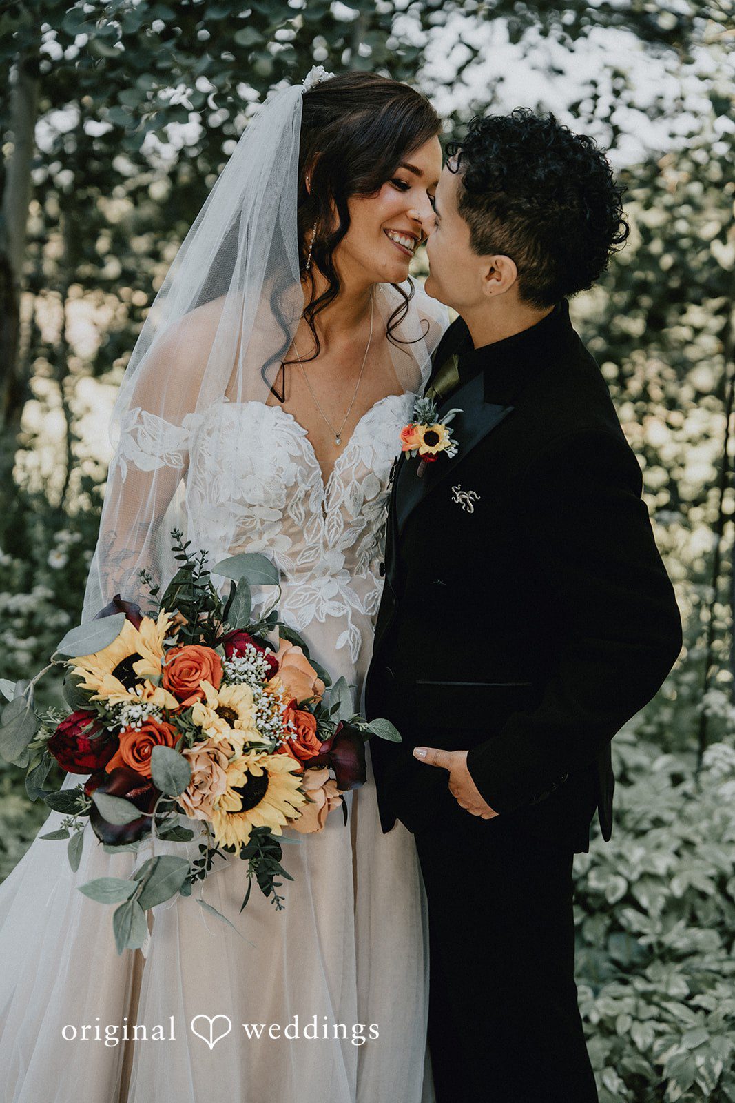 Jennifer + Danielle A bride holds a colorful bouquet while looking affectionately at her partner.