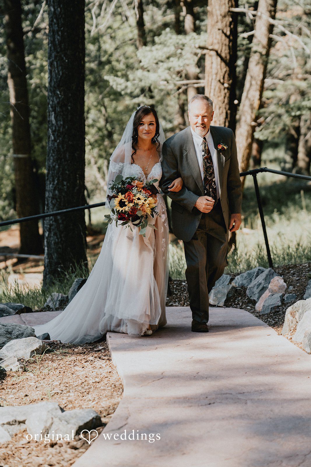 Jennifer + Danielle A bride and man walk together along a paved walkway.