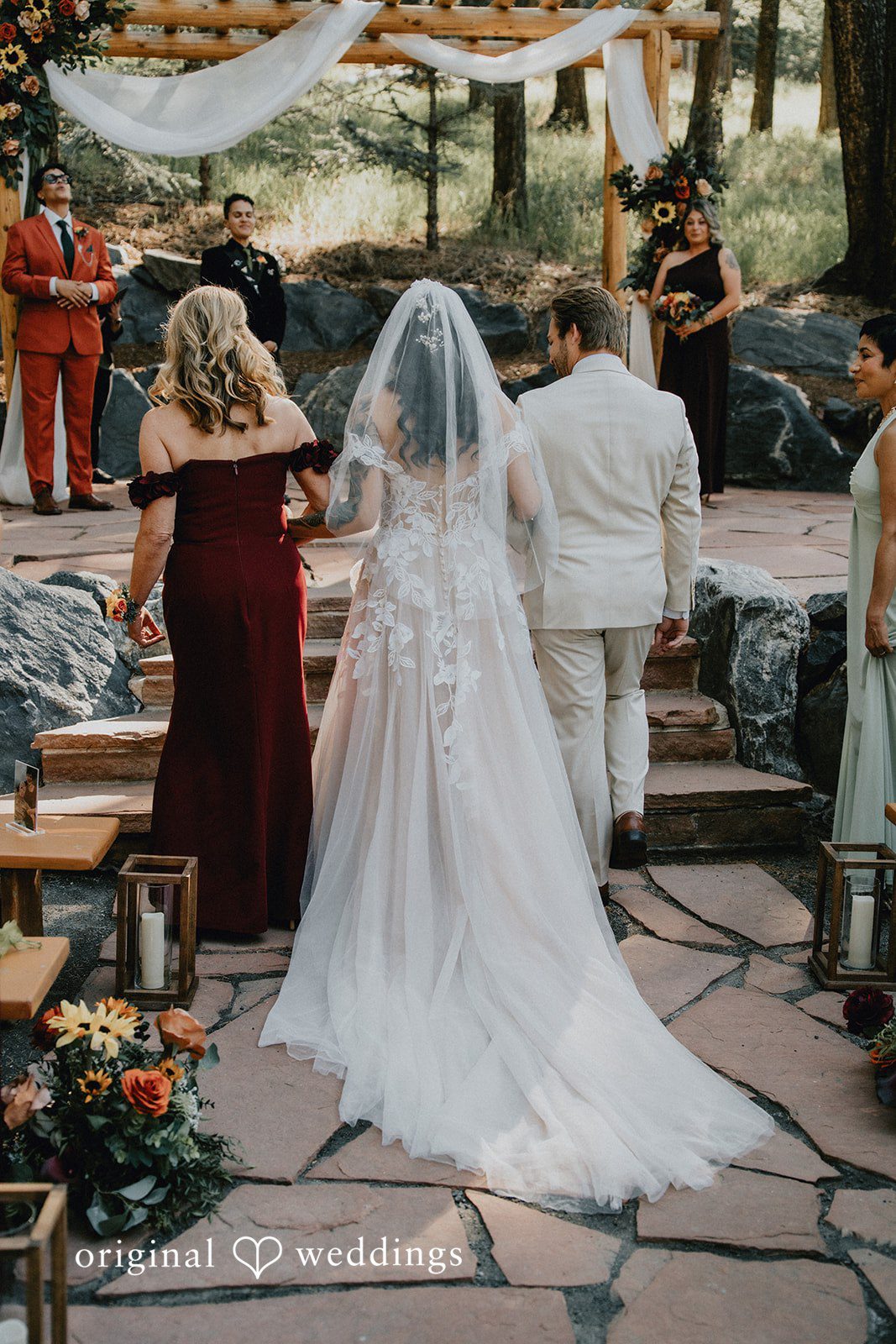 Jennifer + Danielle A bride in a white gown walks down an aisle during a ceremony