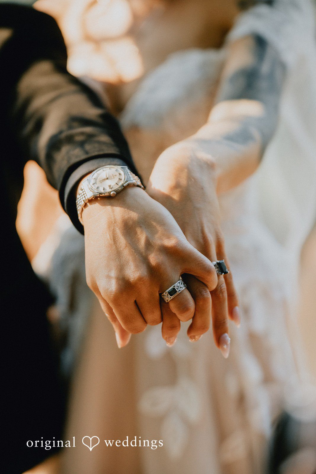 Jennifer + Danielle Close-up of a couple showing off their wedding rings while holding hands.