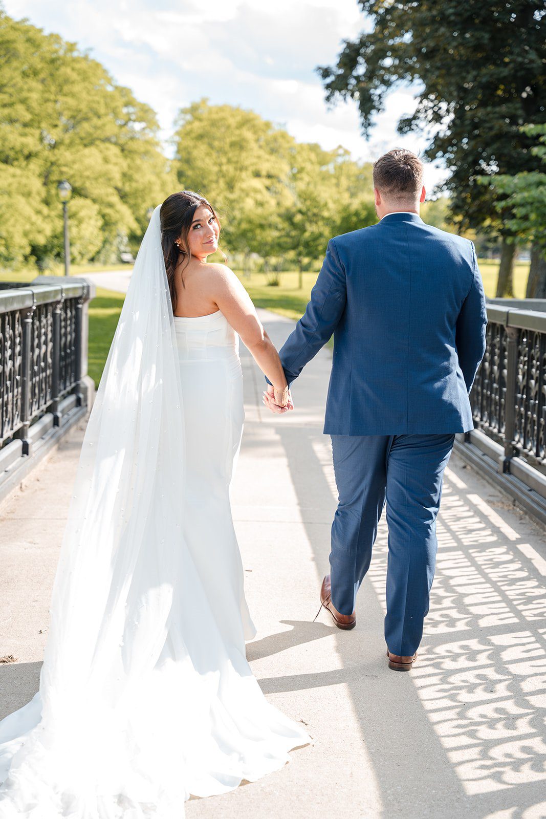 Chelsea + Matthew Bride and groom walking together while holding hands at The Rivulet
