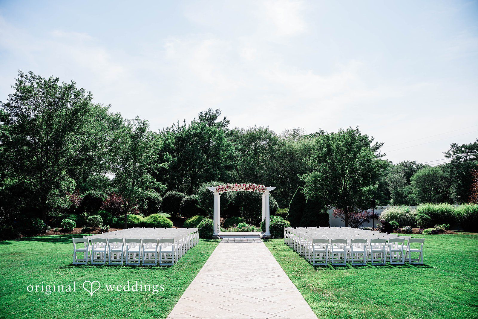An empty wedding ceremony aisle leading to a white archway.