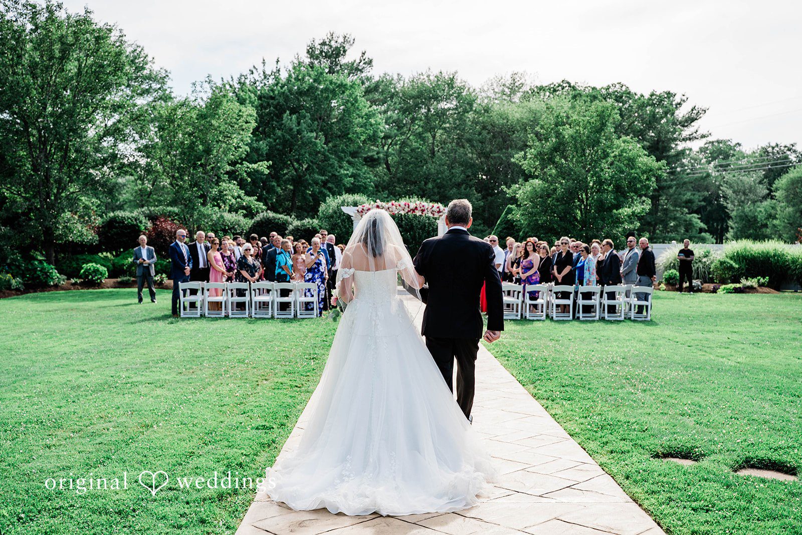A bride in a long train walking toward the wedding altar.
