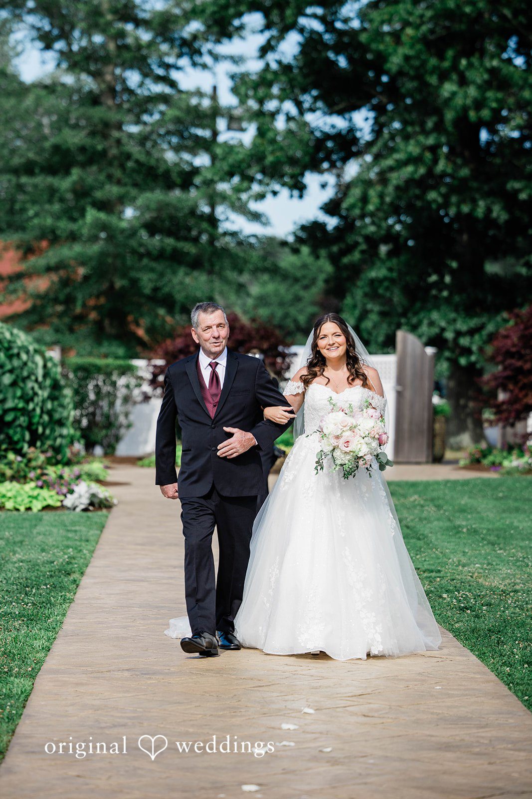 A bride walking down the aisle accompanied by an older man.