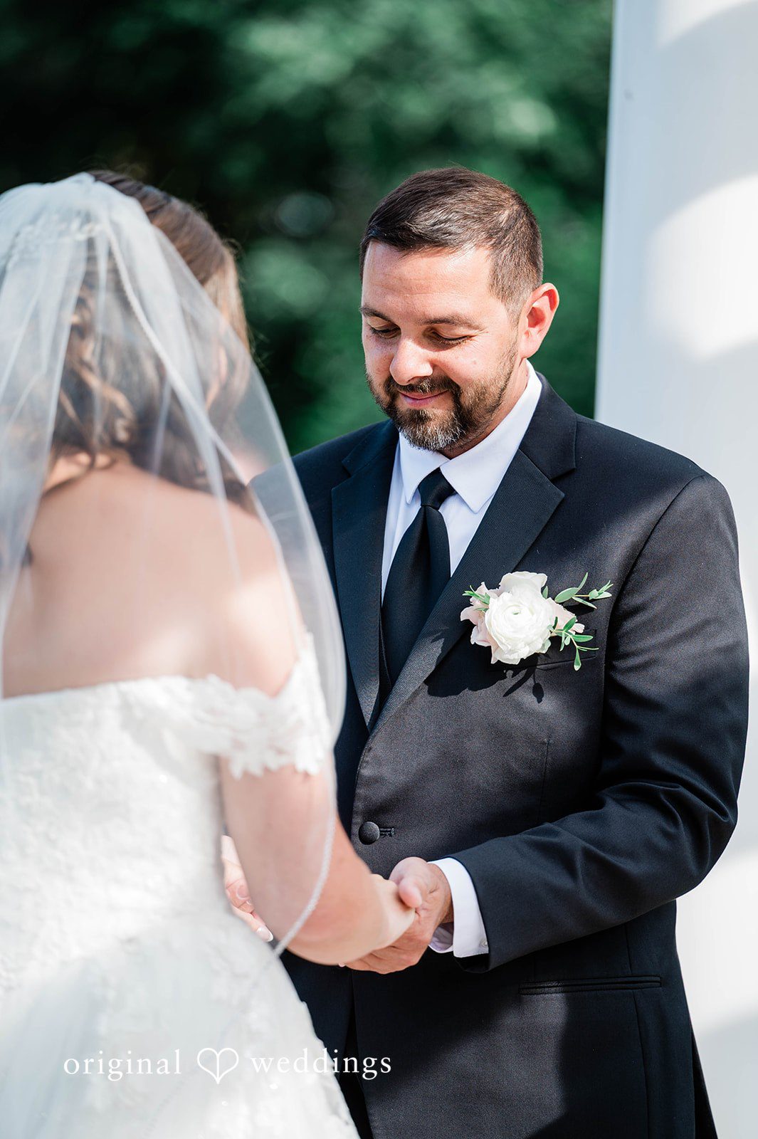 A close-up of a groom smiling at his bride during the ceremony.