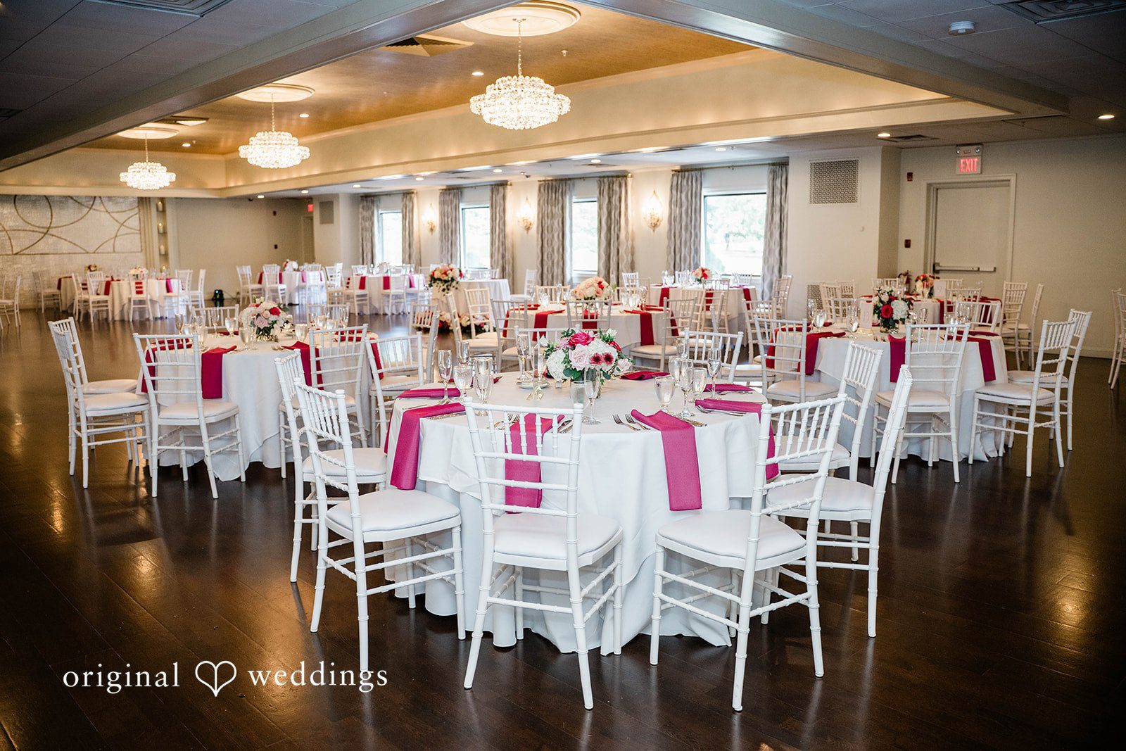 A decorated wedding reception hall filled with empty tables and chairs.