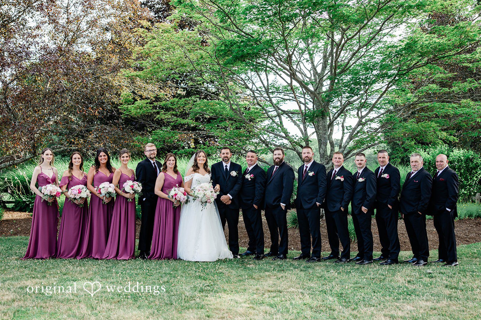 A bridal party standing in a long line for a group photo.