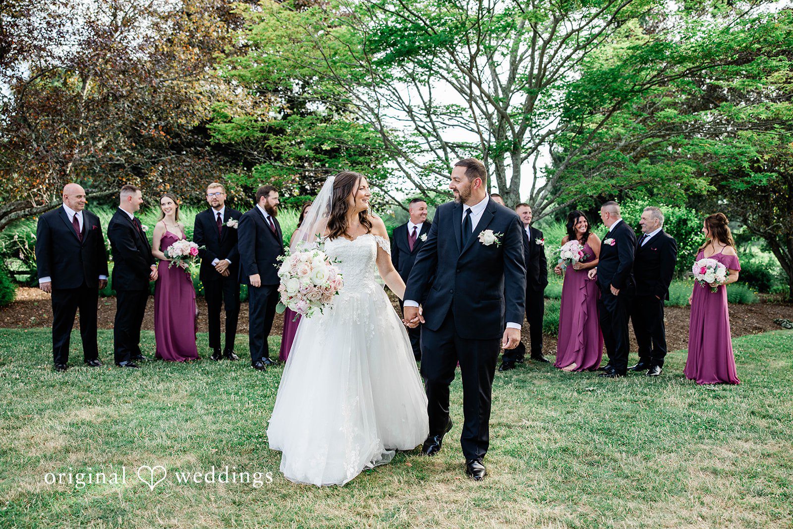A large wedding party standing together on a brick walkway.