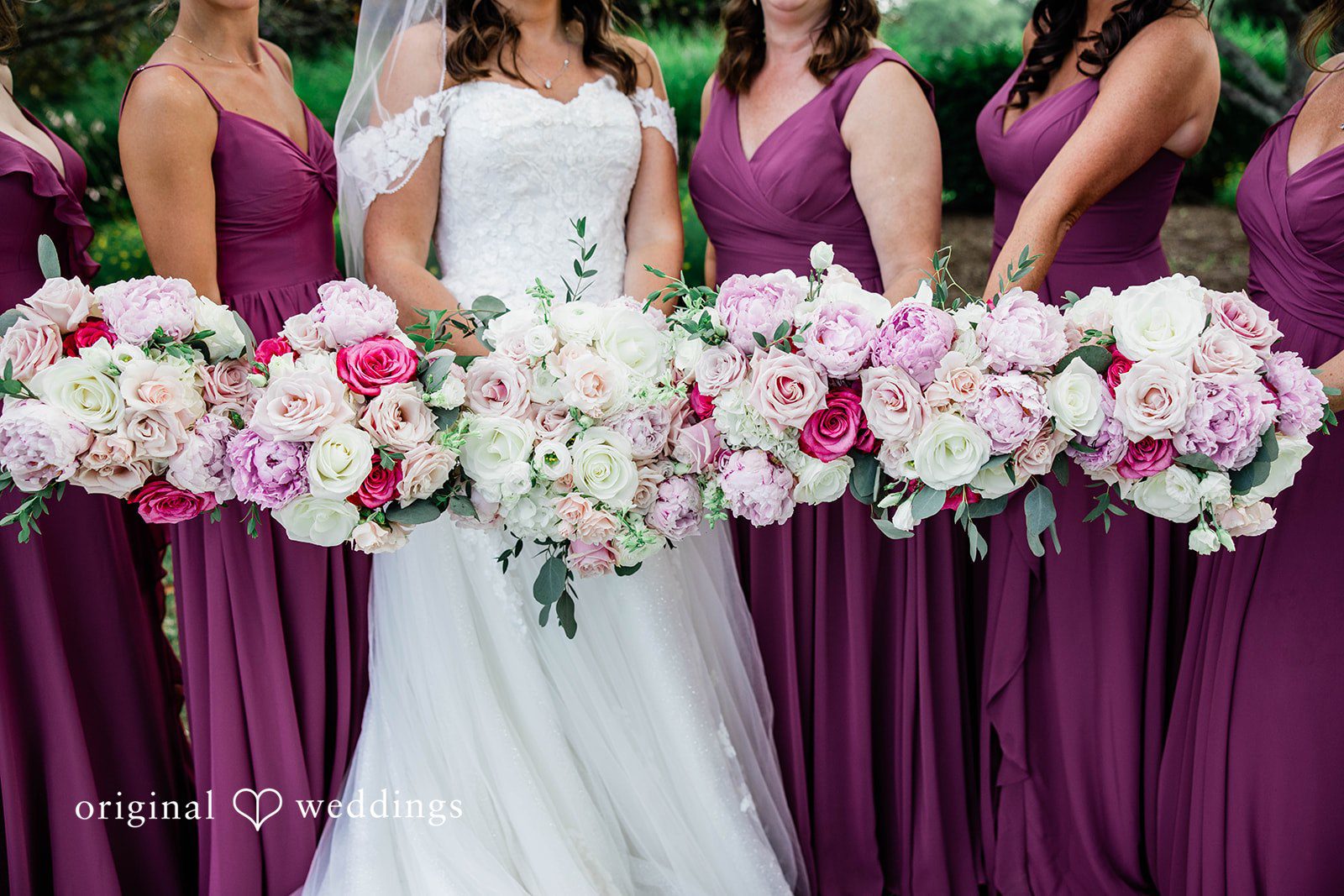 A close-up view of bridesmaids holding large pink and white bouquets.