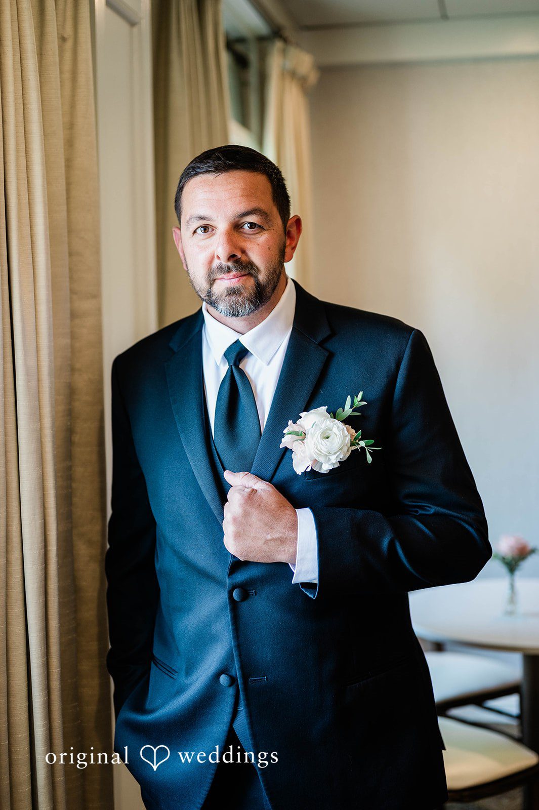 A groom in a black suit posing at The Villa at Ridder Country Club.