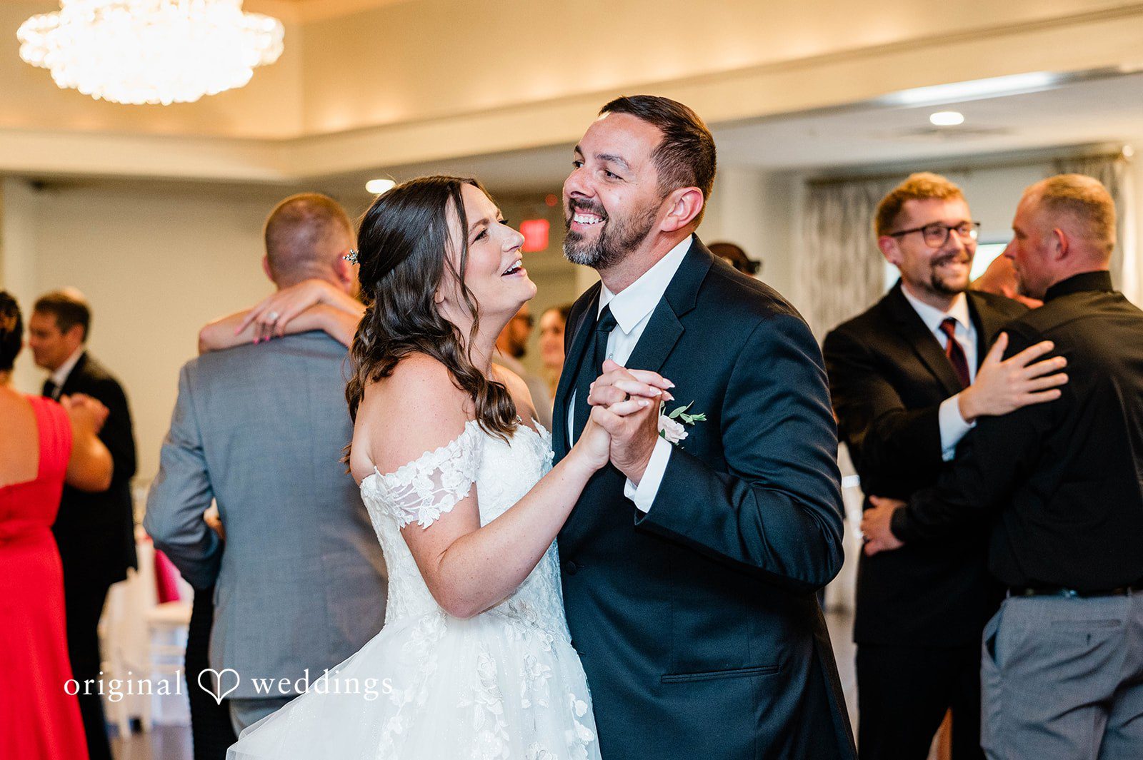 A bride and groom smiling while sharing a dance at their wedding reception.
