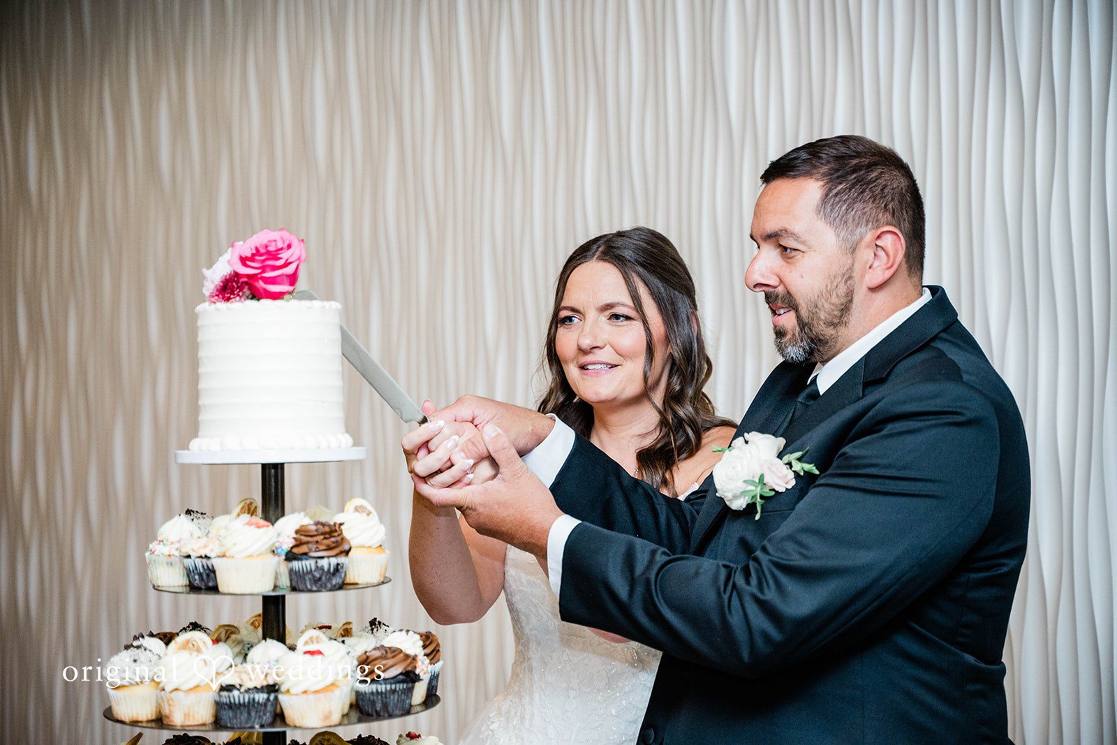 A bride and groom cutting their wedding cake together.