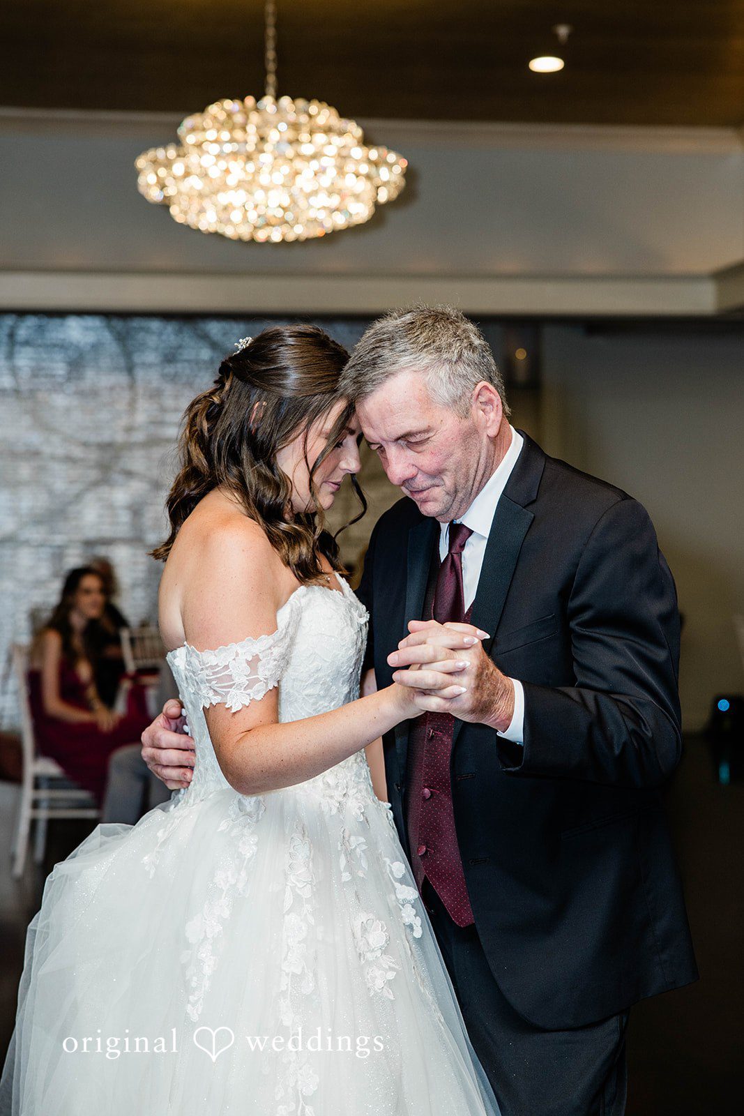 A man in a suit dancing with a bride in reception hall.