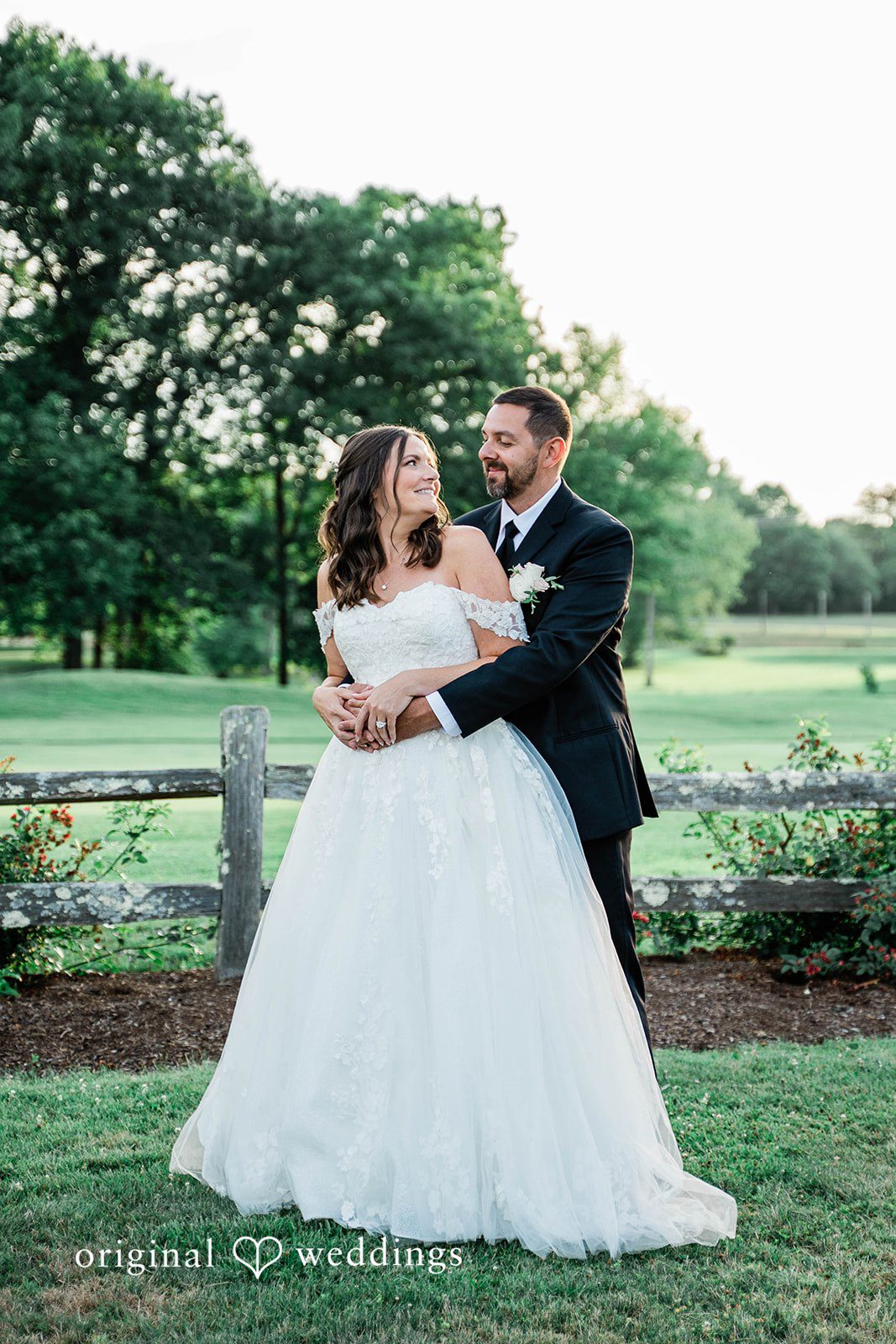 A groom dipping his bride while posing together on a lawn.