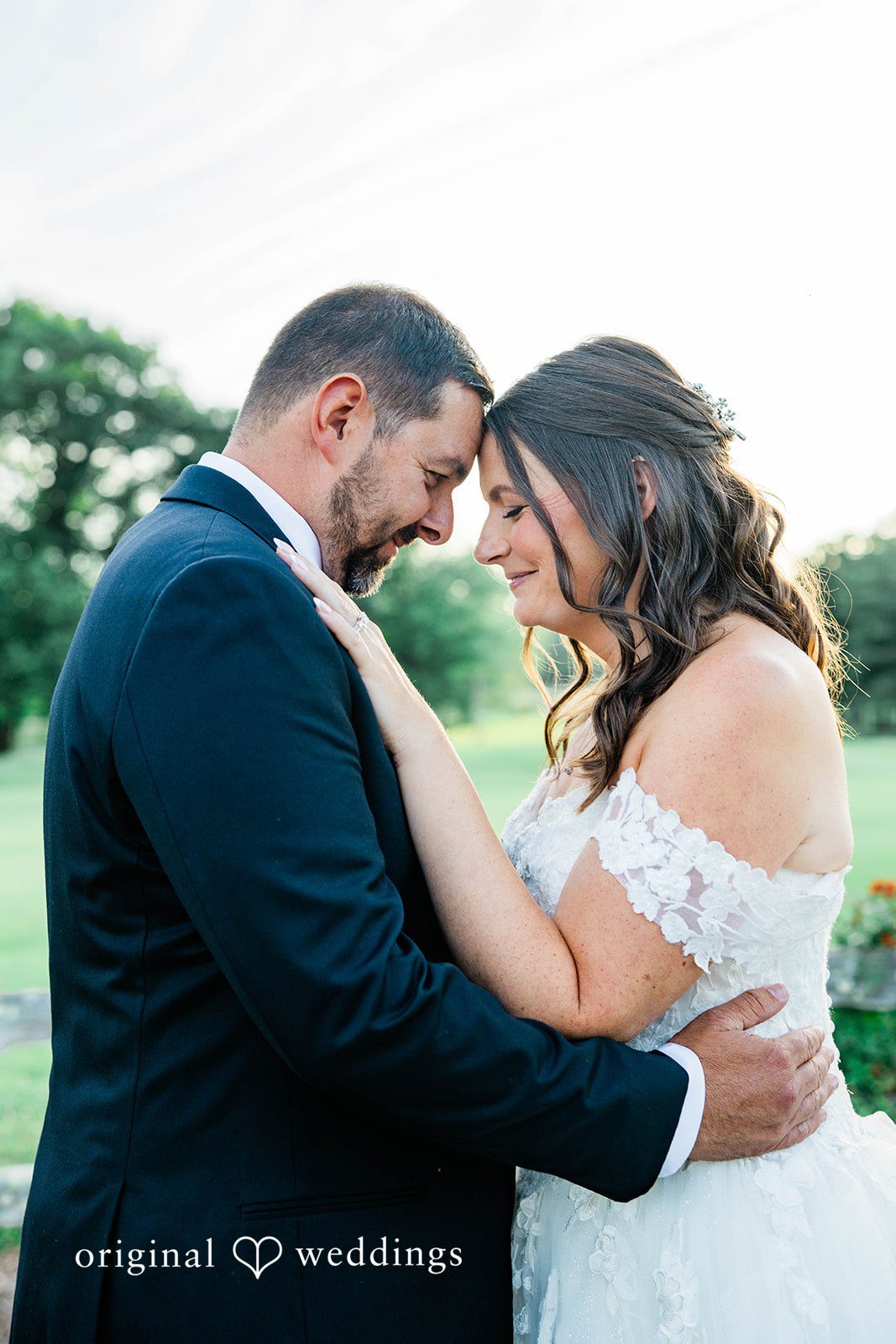A groom holding his bride's hand while posing together.