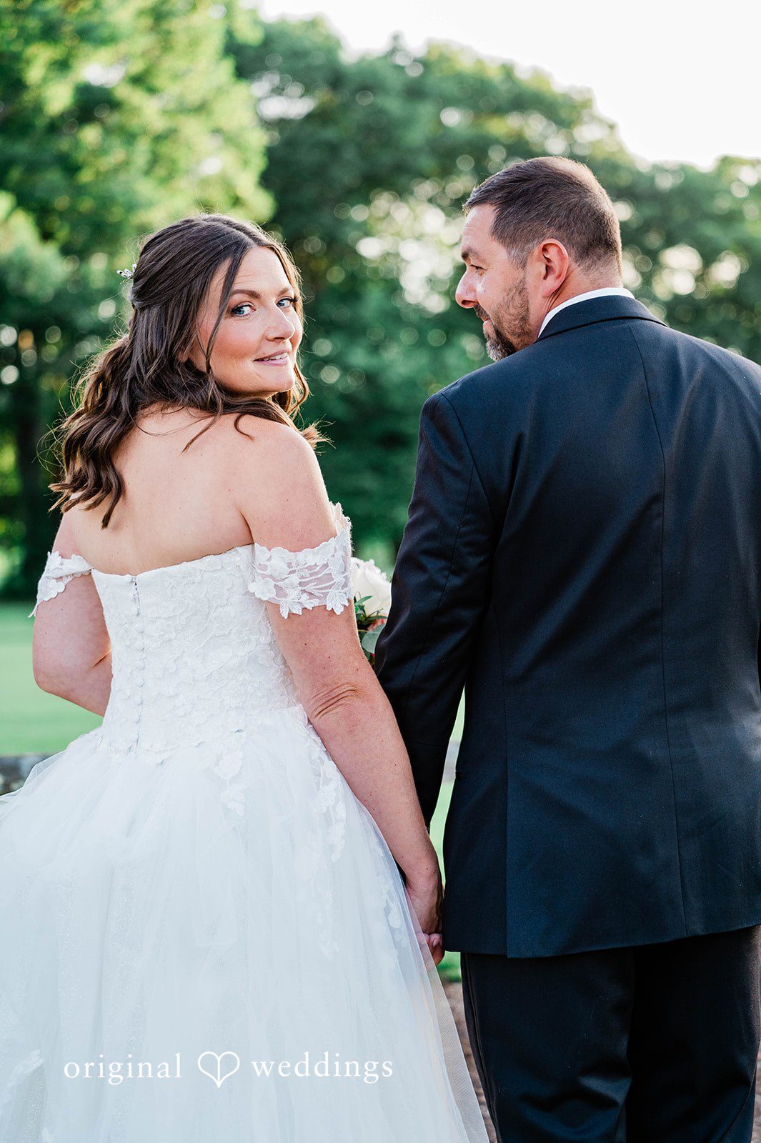 A groom lovingly looking at his bride as she smiles in her dress.