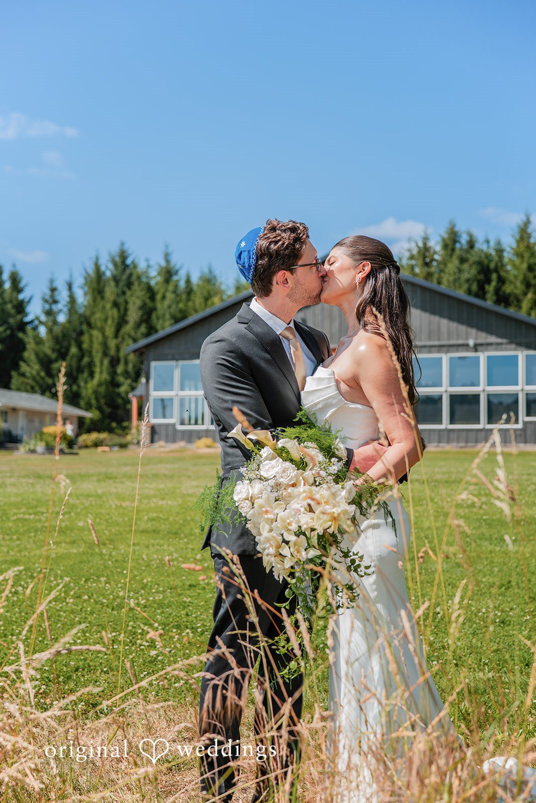 Zechariah + Tova A groom dipping his bride backward while sharing a kiss on a paved stone walkway.
