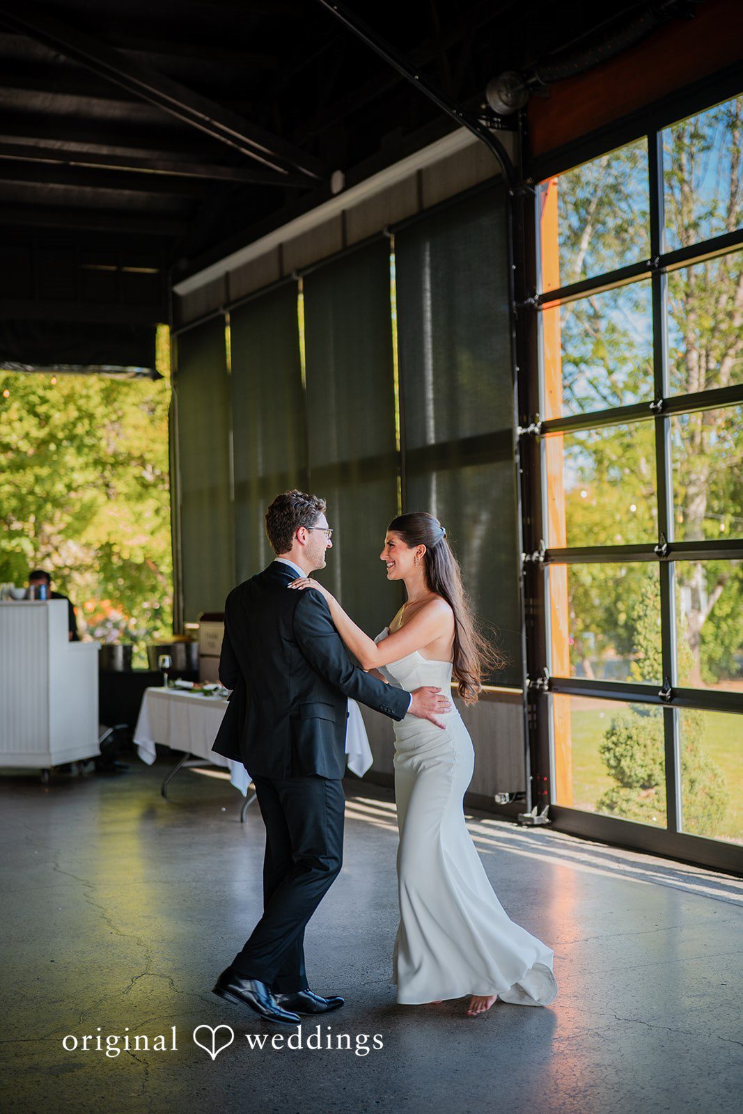 Zechariah + Tova A bride and groom sharing their first dance in the center of a spacious reception hall.