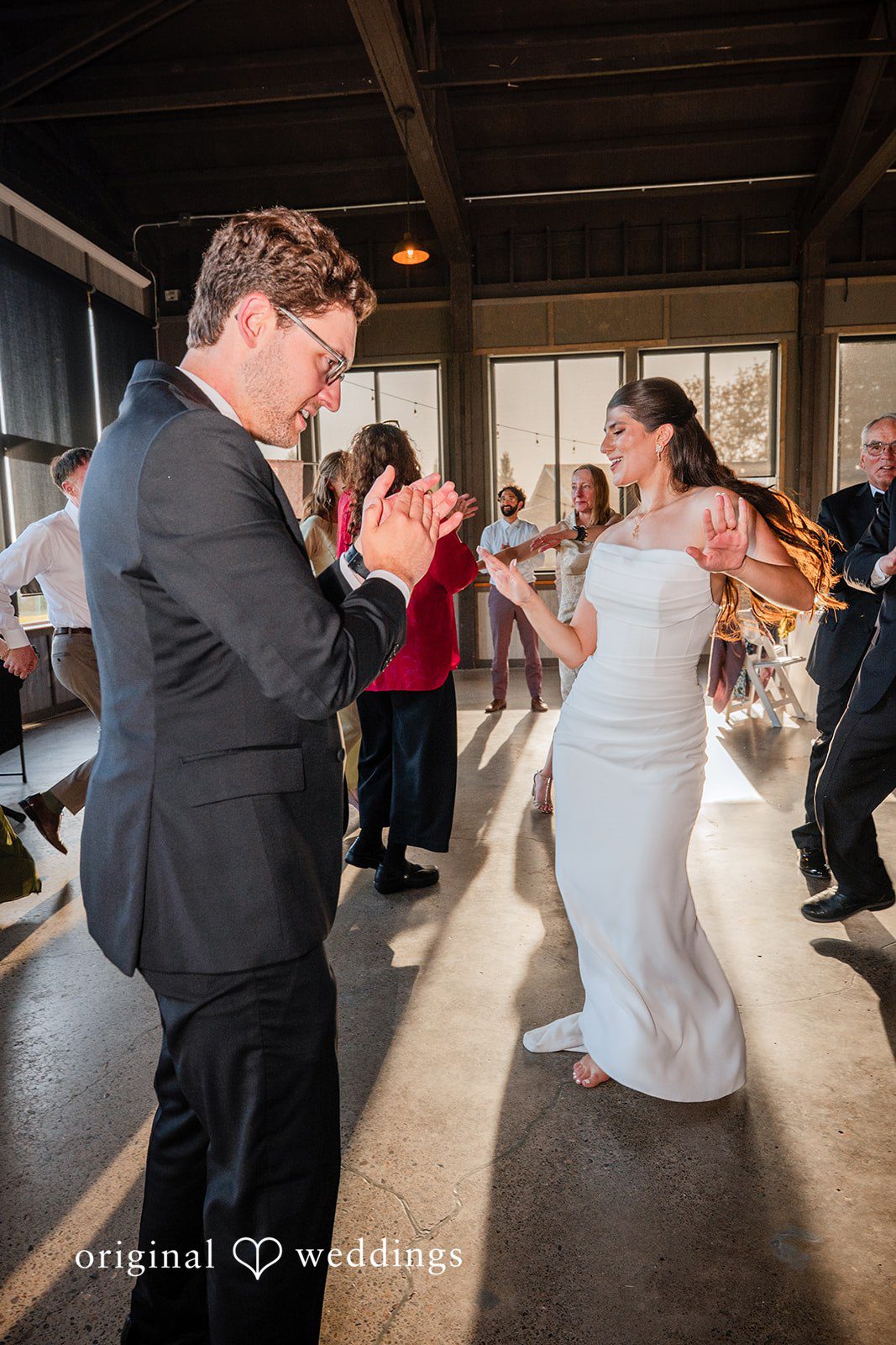 Zechariah + Tova A group of wedding guests dancing dynamically in the middle of a reception room.
