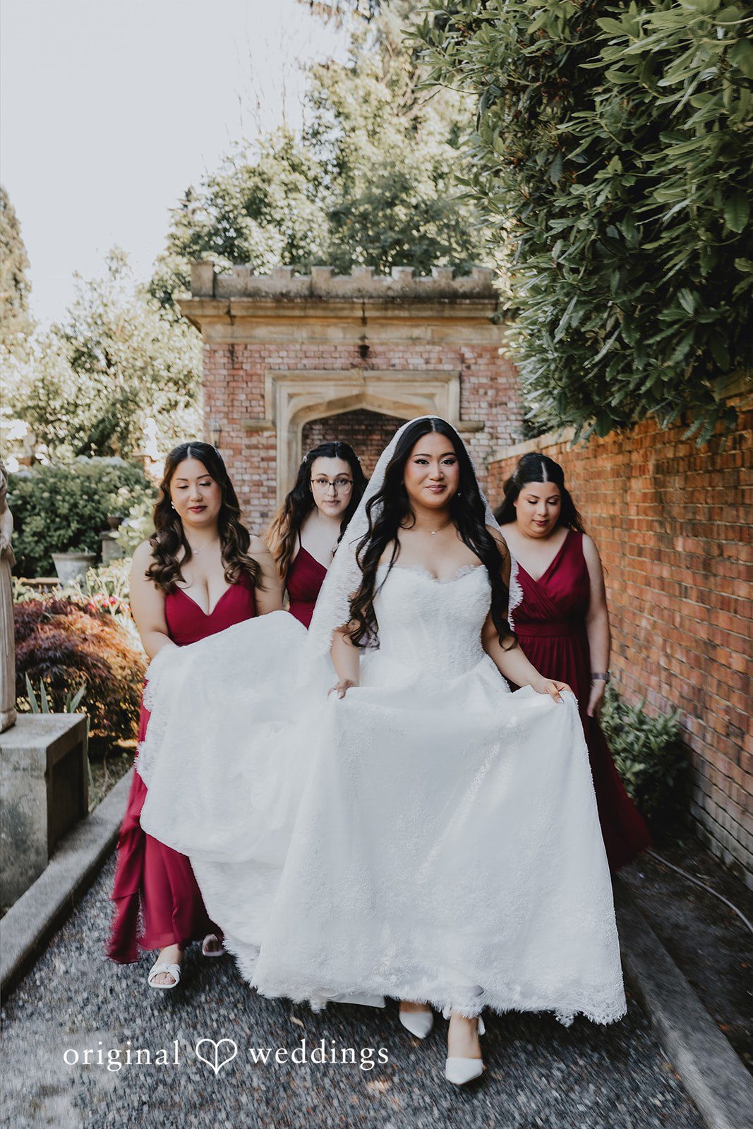 Sharmaine + Ronald A bride posing on a staircase with her bridesmaids in red dresses.