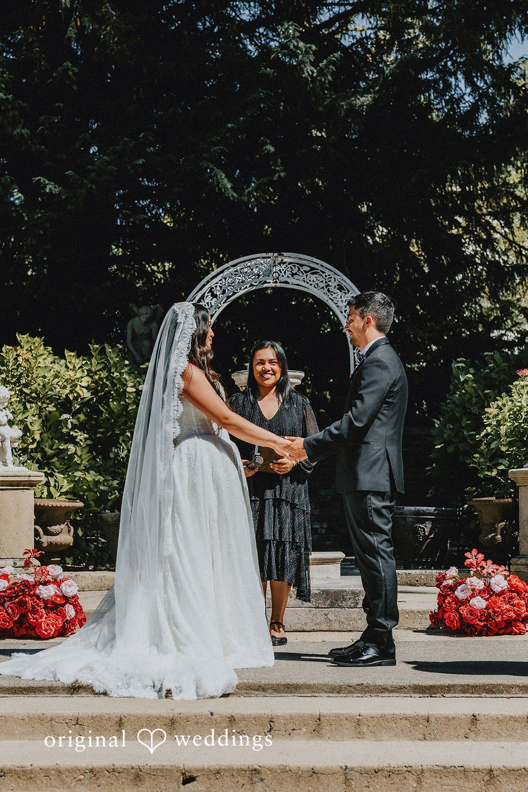 Sharmaine + Ronald A bride and groom exchanging vows under a circular floral archway.