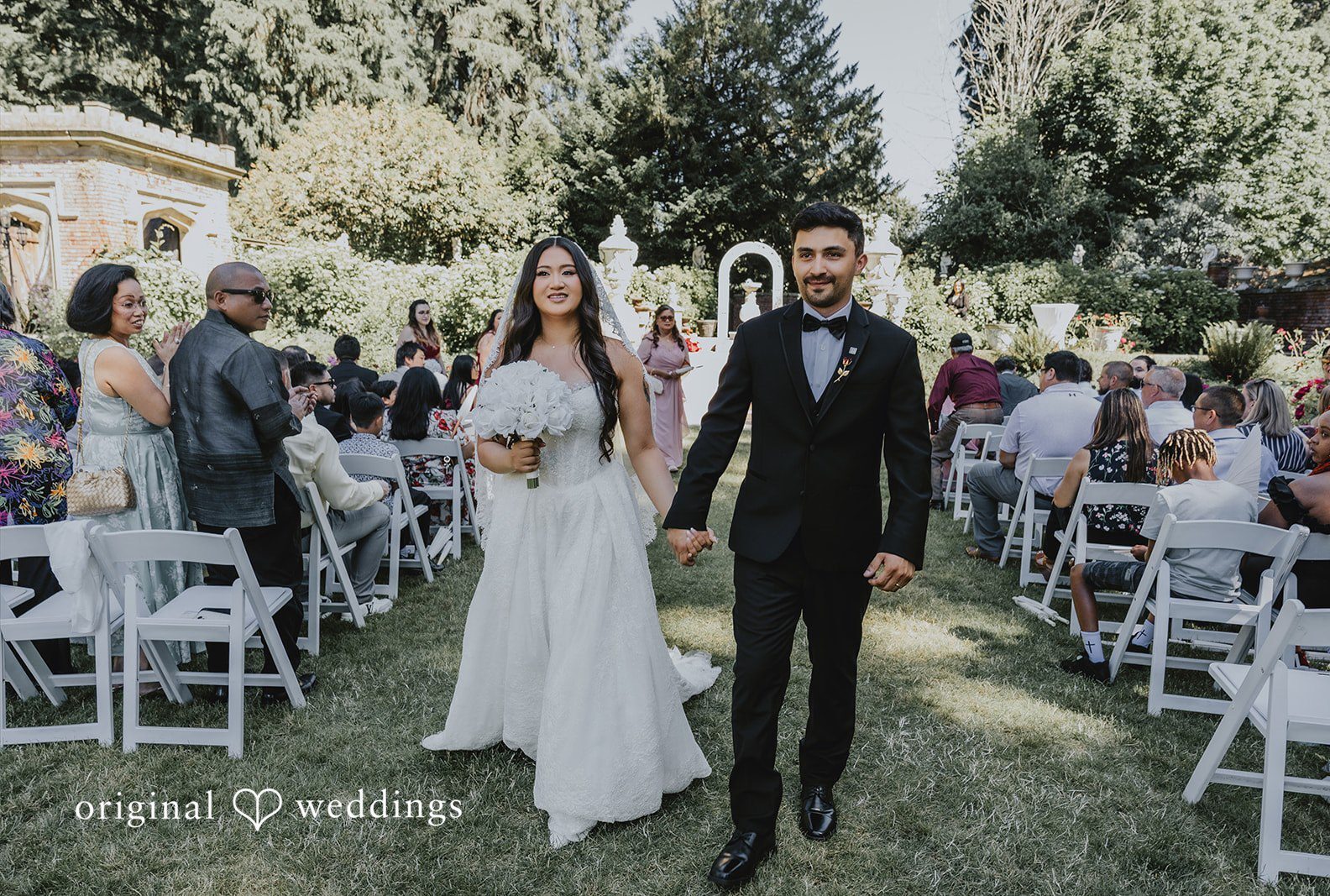 A newlywed bride and groom smiling as they walk down the aisle together captured by Seattle wedding photographers from Original Wedding at Thornewood Castle