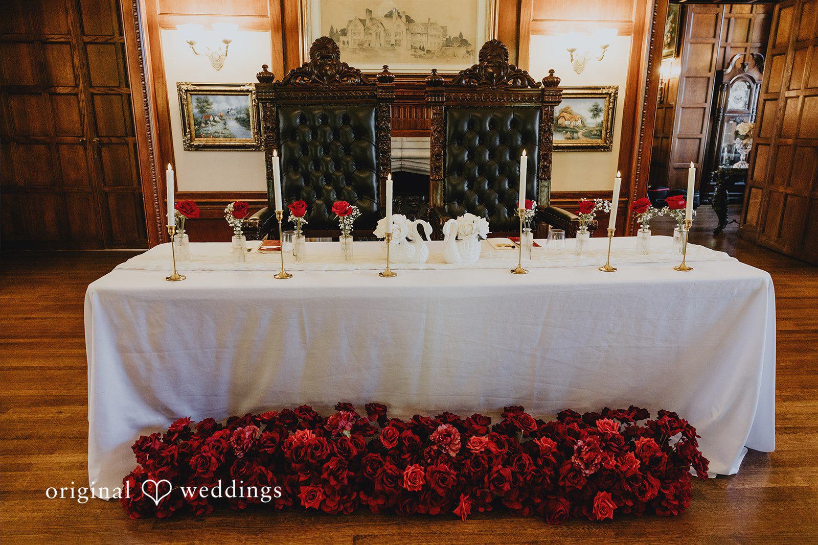 Sharmaine + Ronald A long banquet table draped in white cloth with a red floral display underneath.