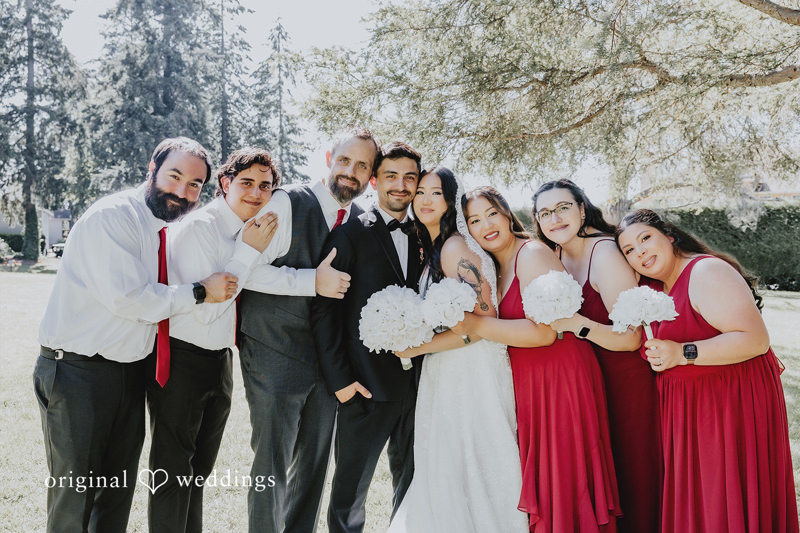 Sharmaine + Ronald A large wedding party in formal attire posing and smiling together.
