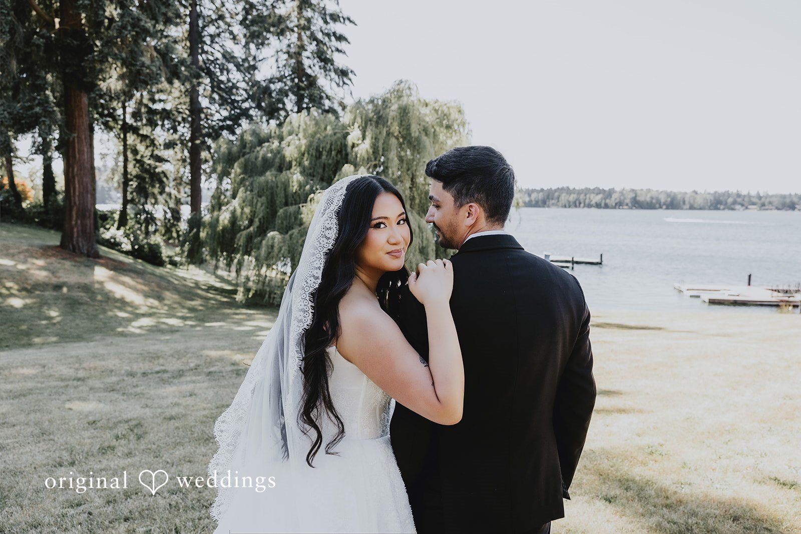 Sharmaine + Ronald A bride and groom holding hands while looking at each other near the water.