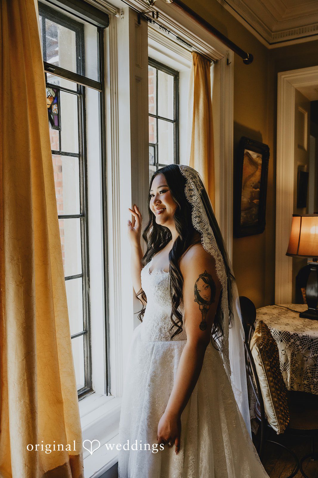 Sharmaine + Ronald A bride looking out a window while holding her bouquet.